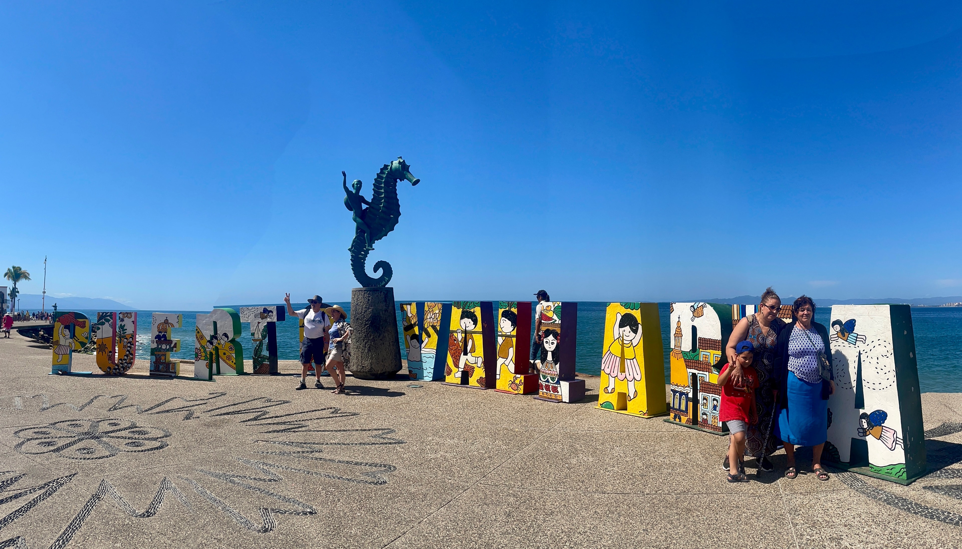 A shot of a couple standing in front of Puerto Vallarta sign on the beach.