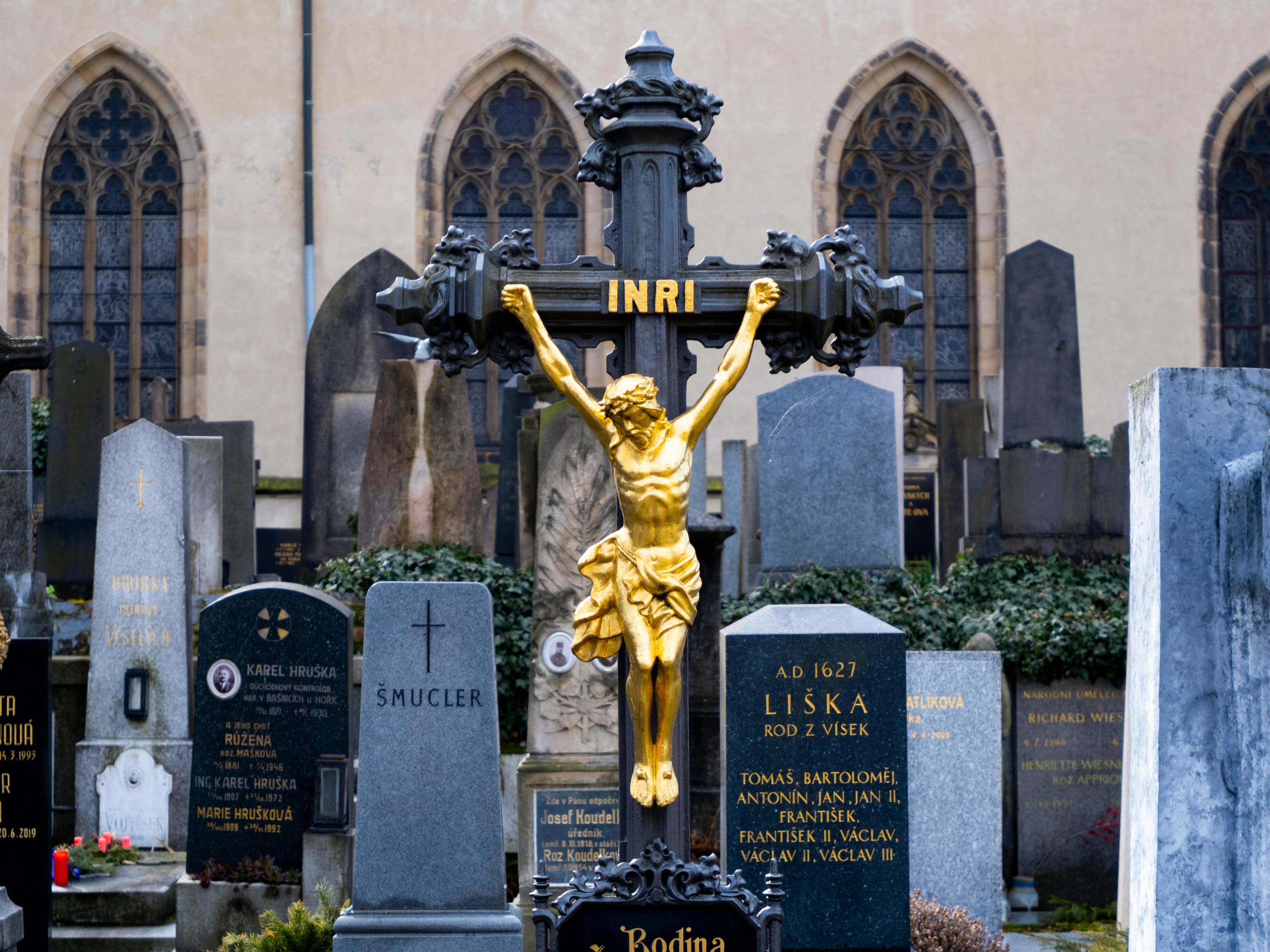 The image portrays a cemetery with a golden crucifix and various tombstones, evoking a somber and reflective mood.