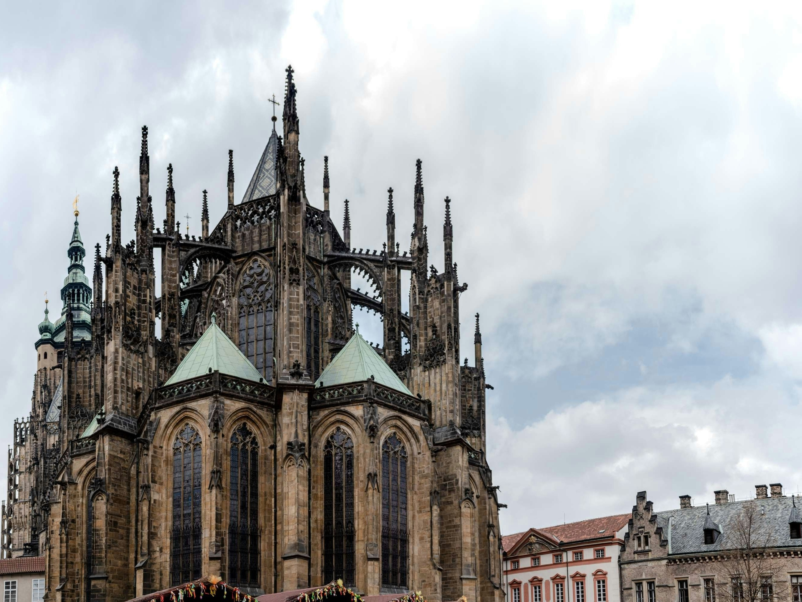 The image showcases a grand Gothic-style cathedral under a cloudy sky, highlighting its intricate architecture and spires.