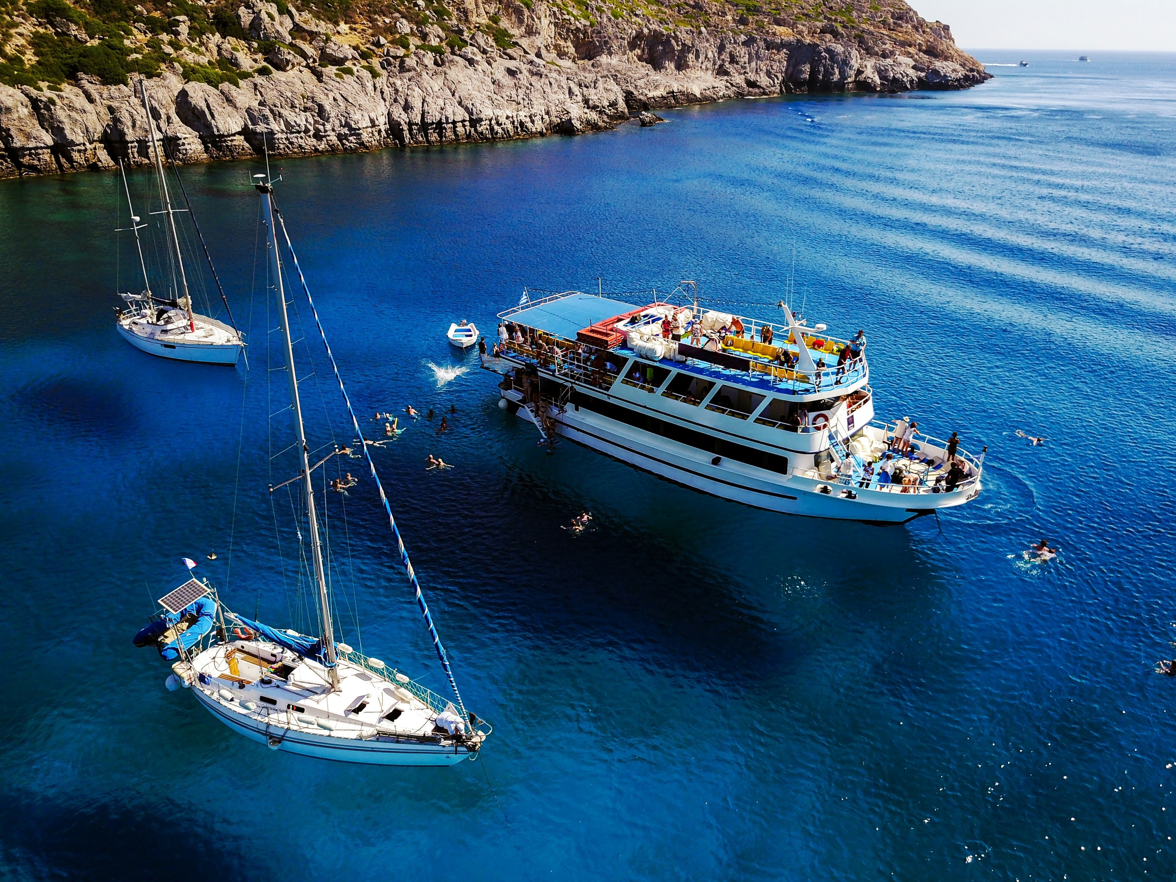 A serene sailboat journey on a clear blue sea, framed by majestic cliffs.