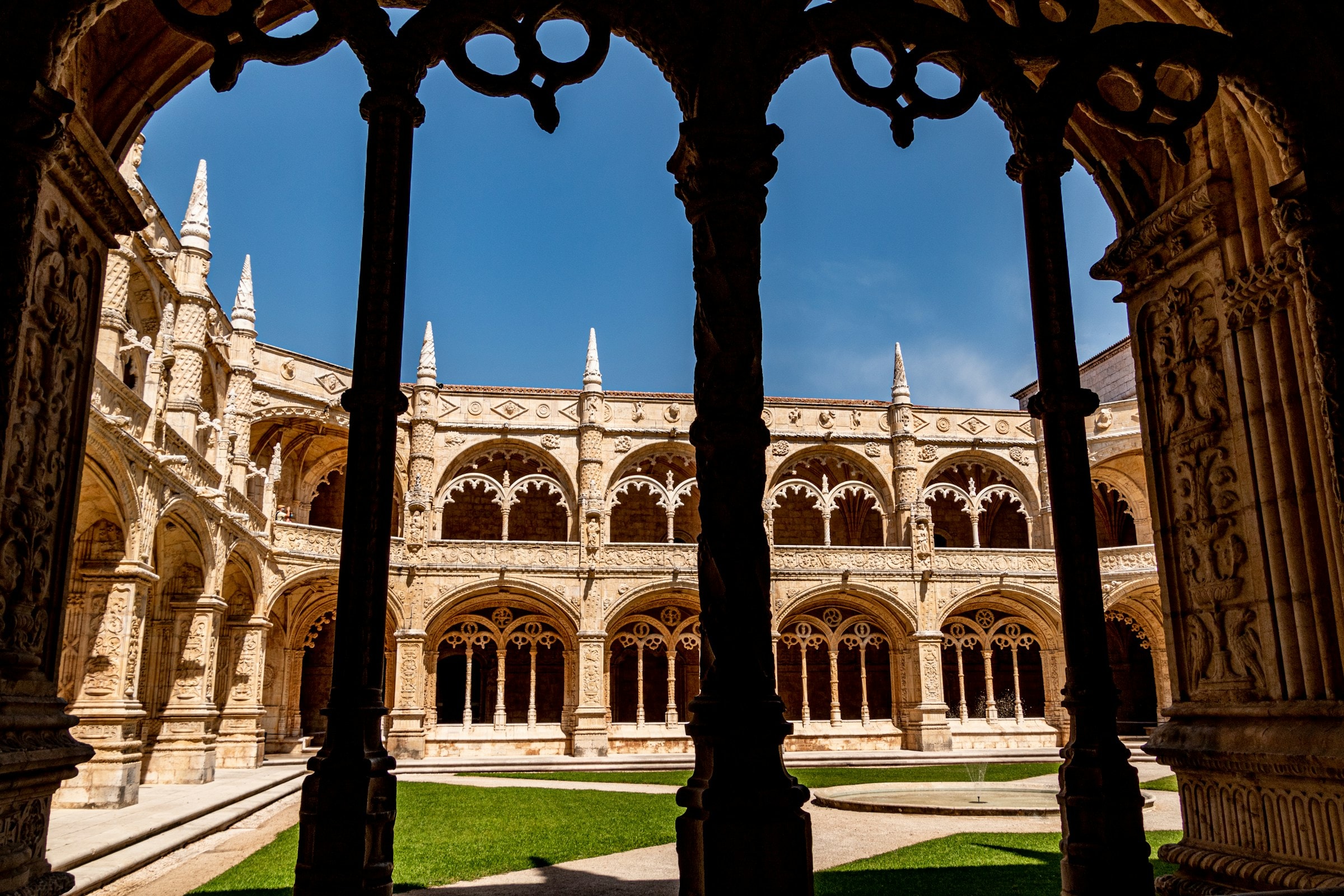 An inside view of the courtyard of the Jeronimos Monastery, with intricate, stone architecture and carvings.