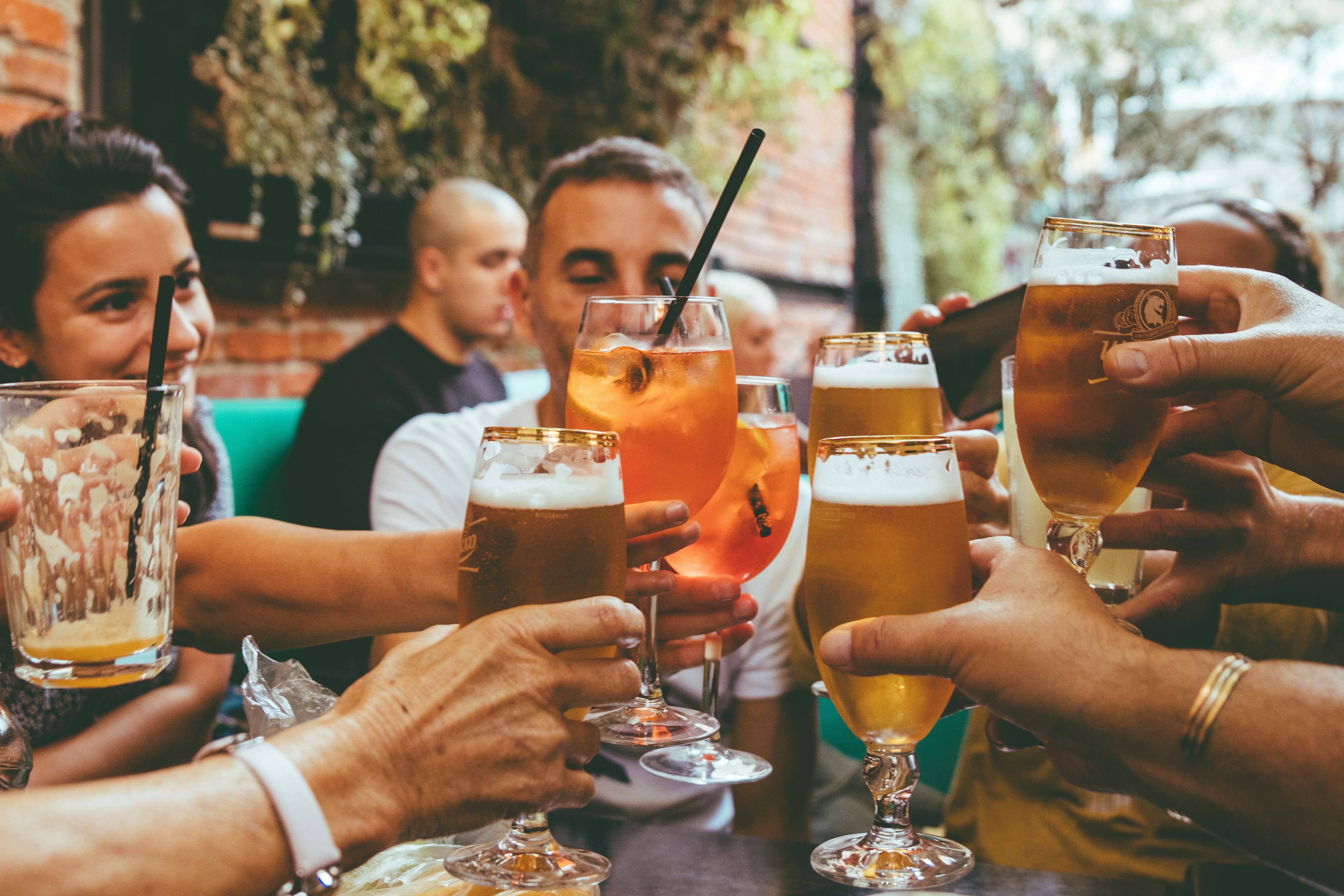 A group of people toasting each other with drinks at an outdoor bar