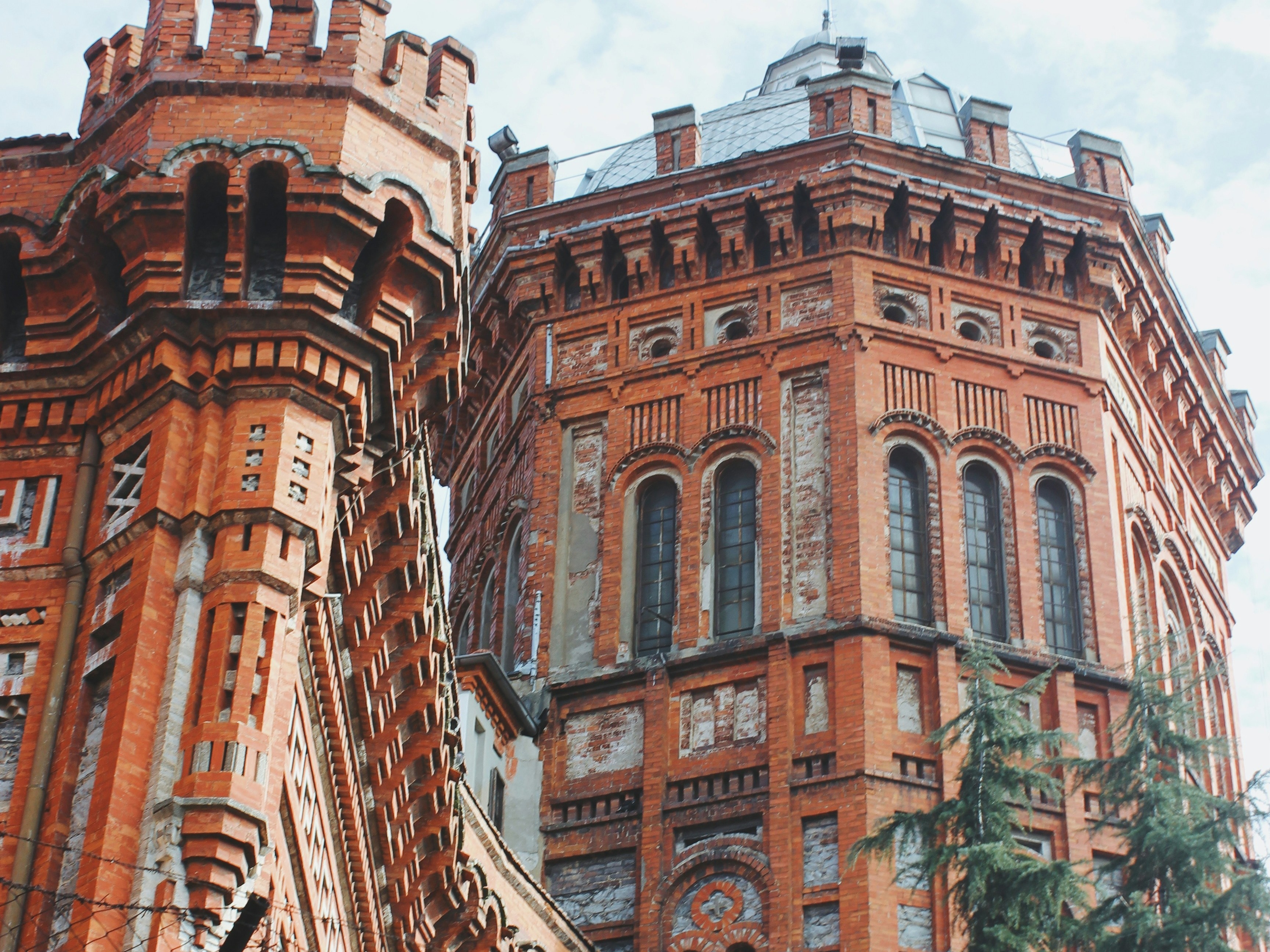 The image showcases a towering, ornate red brick building with intricate architectural details against a clear sky.