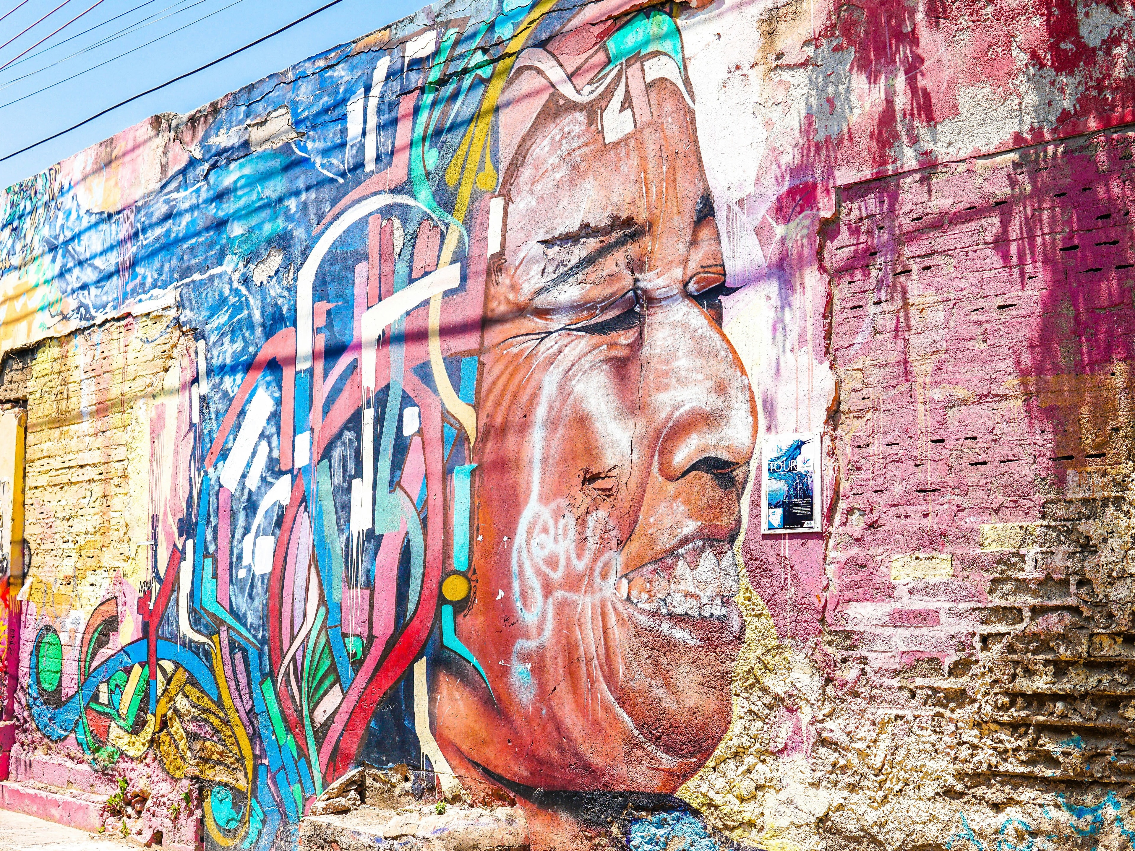 A vibrant graffiti mural of a person’s face on an urban wall.