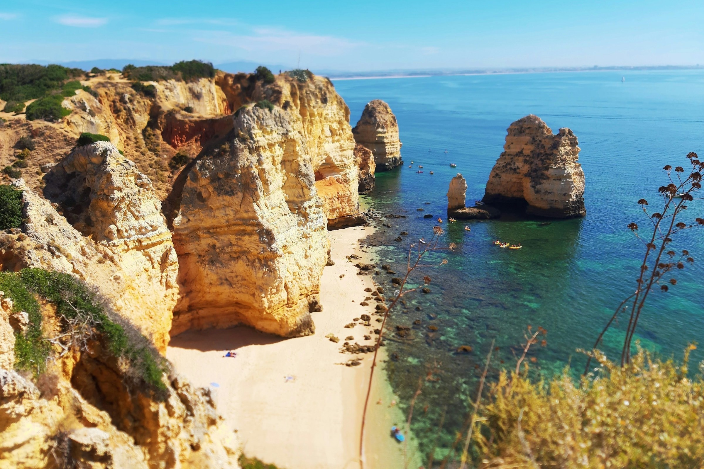 Golden cliffs descending down to the sand and shore in Ponta da Piedade, Lagos on a sunny day.