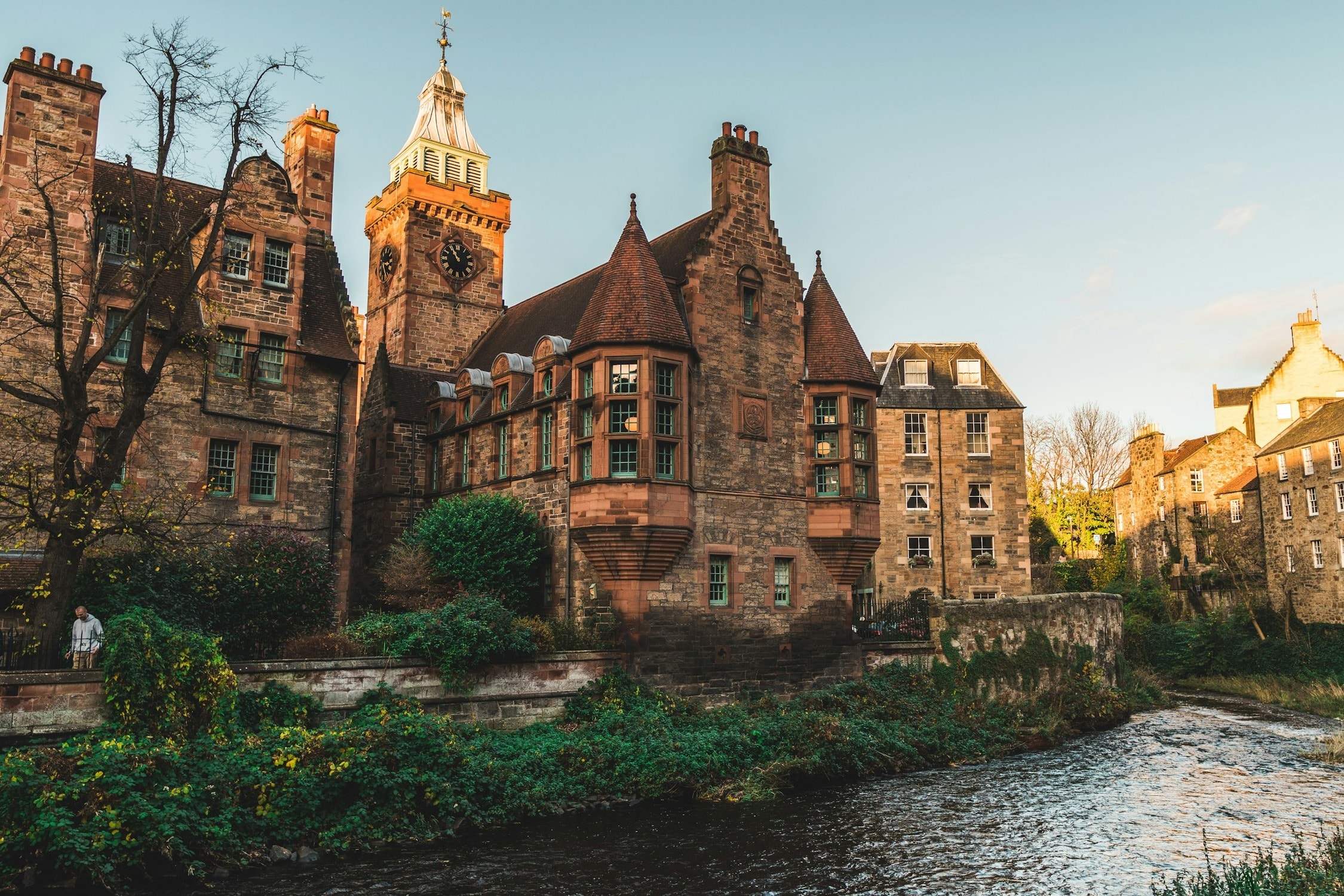 A historic brick building next to a river stream 