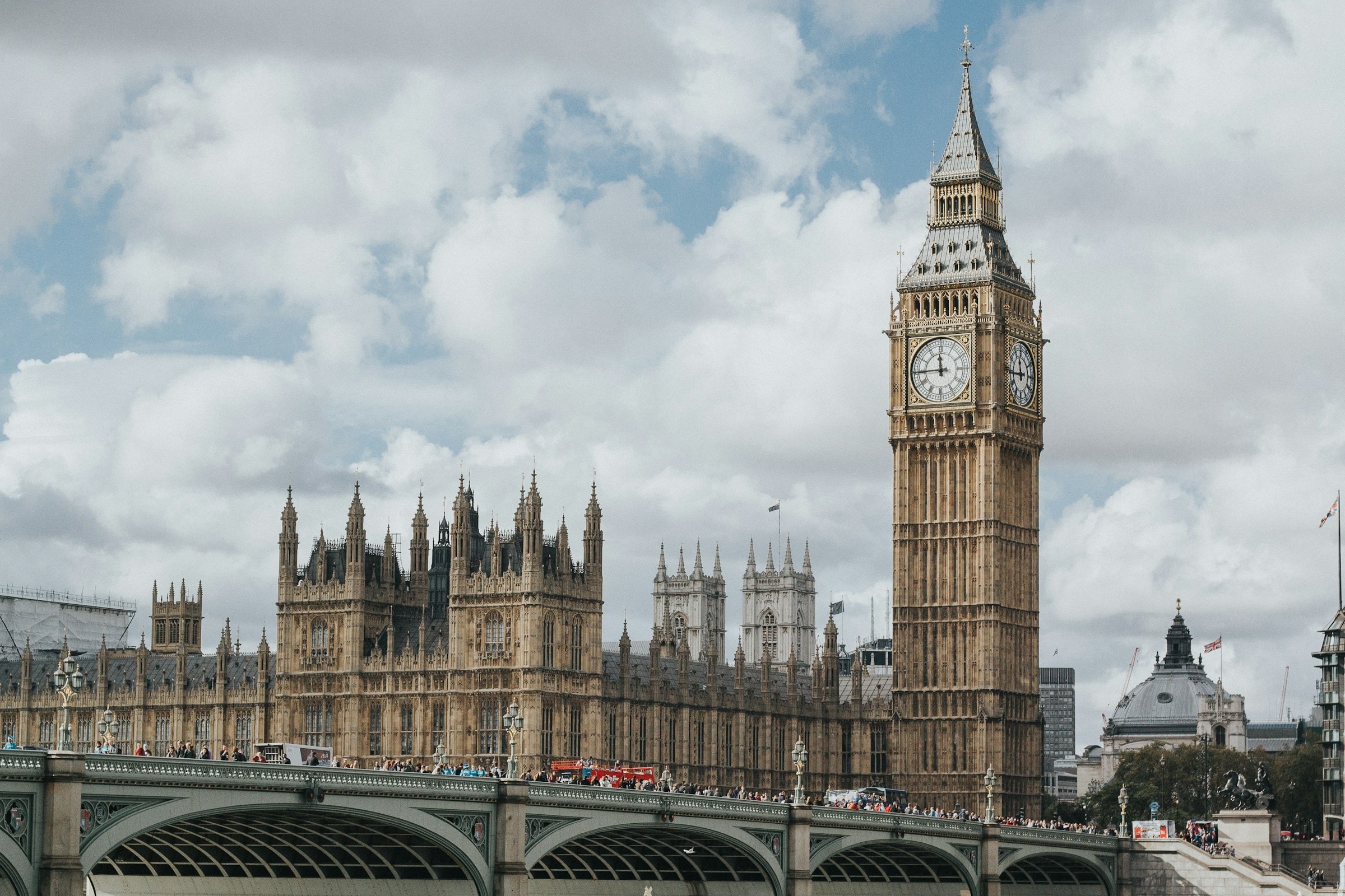 A tall clock tower next to parliament buildings during the daytime