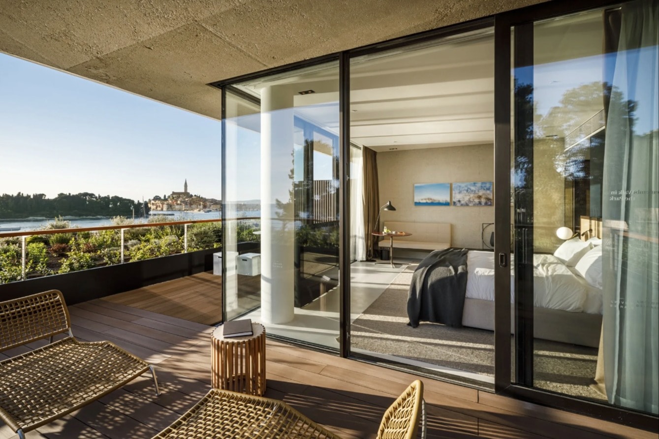 corner bedrooms suite with glass sliding door to a wooden deck with water views