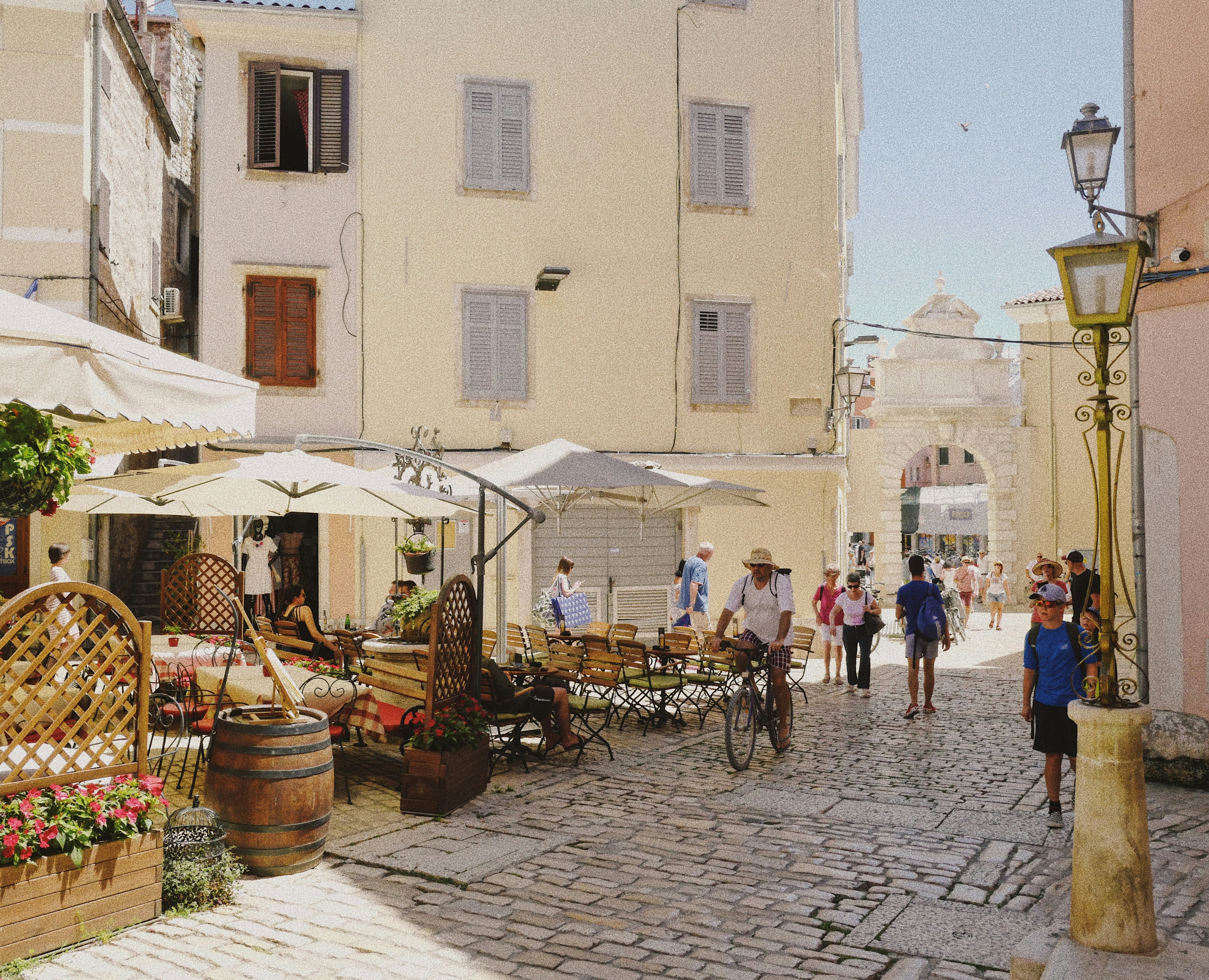 A picturesque European street with people, traditional architecture and a horse-drawn carriage.