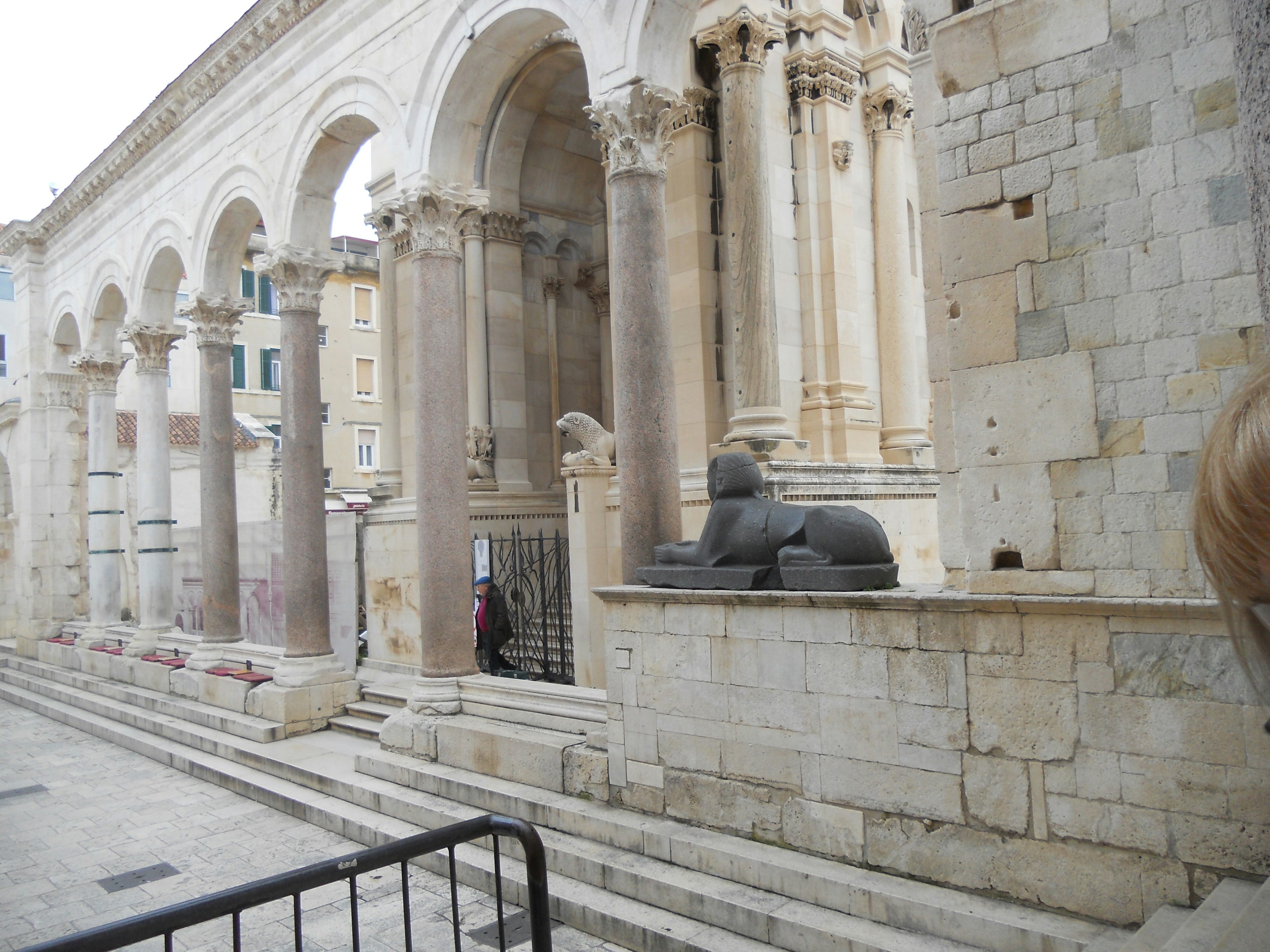 An ancient architectural structure with columns, arches, and a sphinx sculpture.