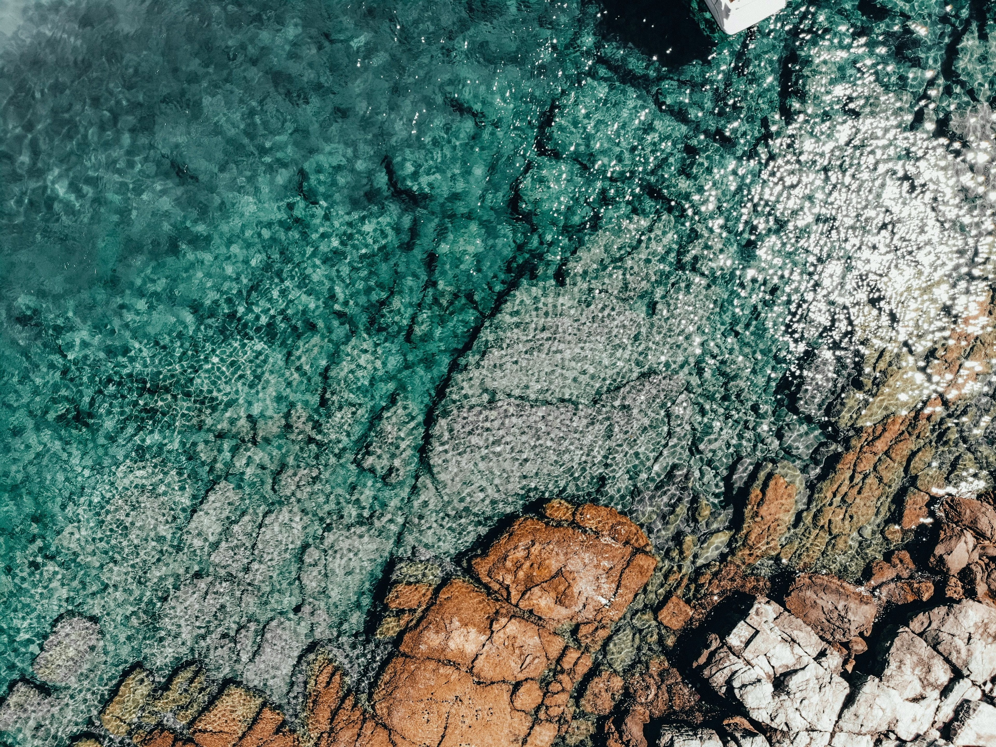 An aerial view of a rocky shoreline with clear, turquoise waters.