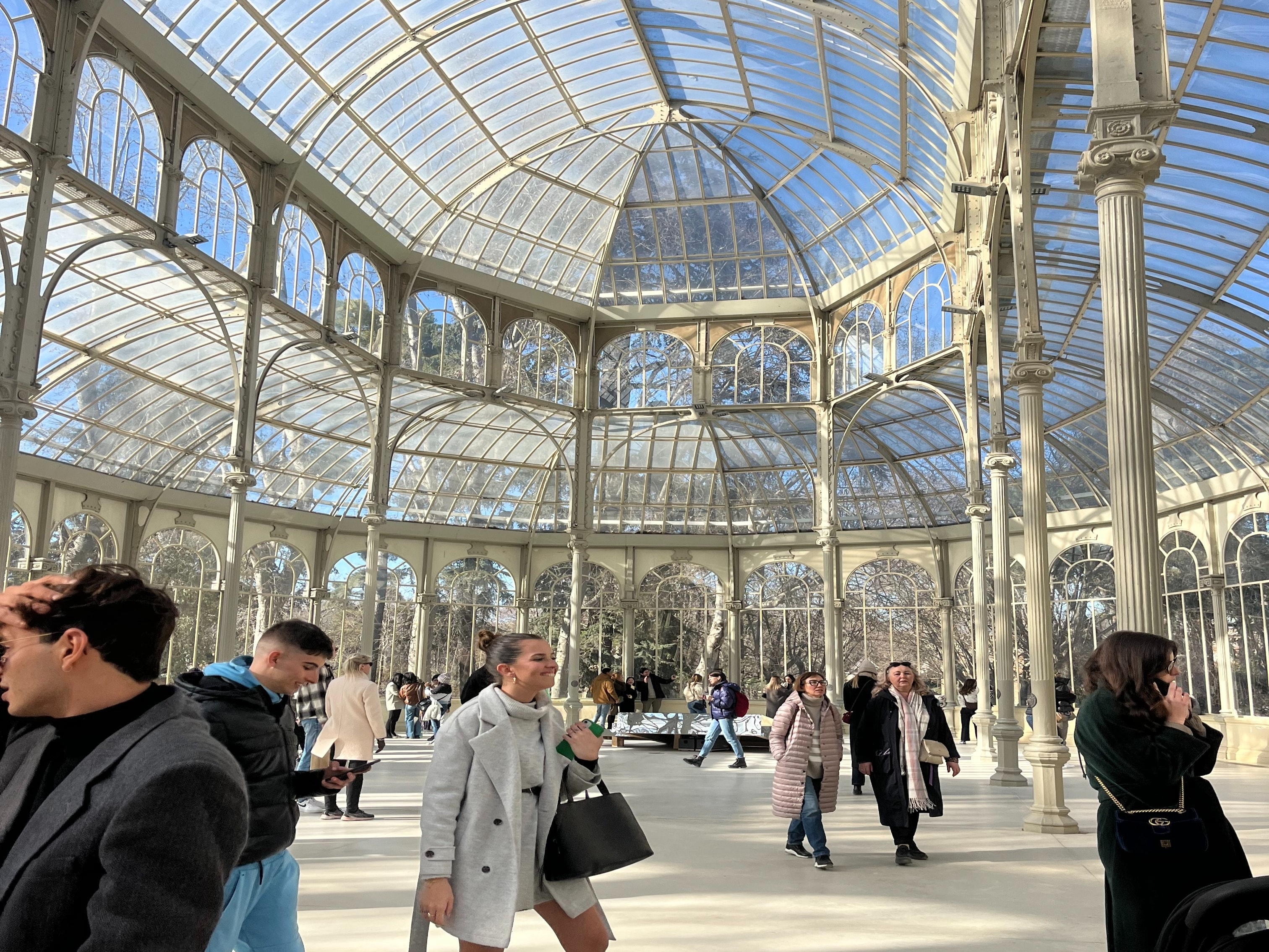 A serene indoor promenade bathed in natural light from a glass ceiling, with visitors enjoying the open space.