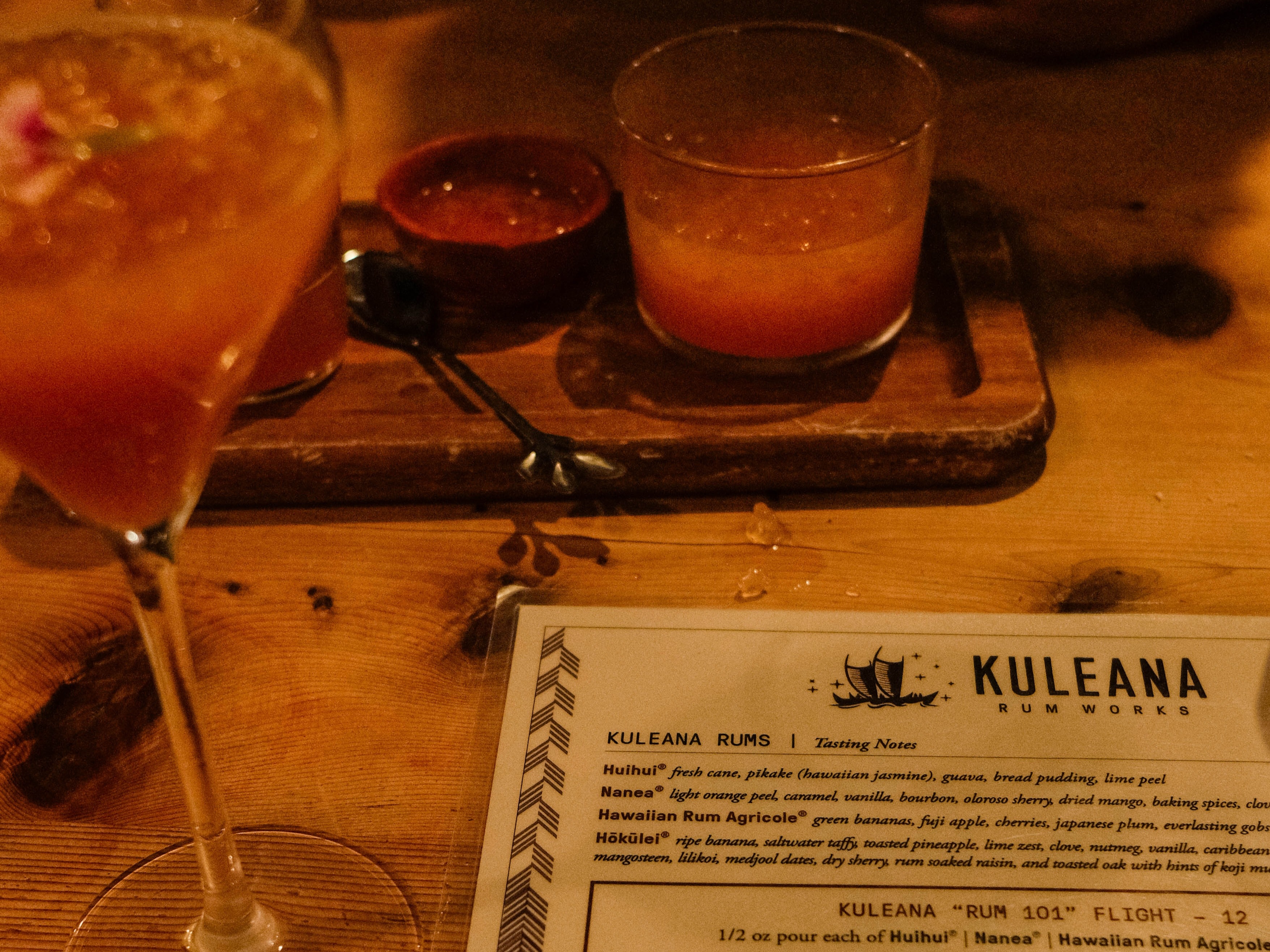 A trio of rum cocktails accompanied by a menu, invitingly presented on a rustic wooden table.