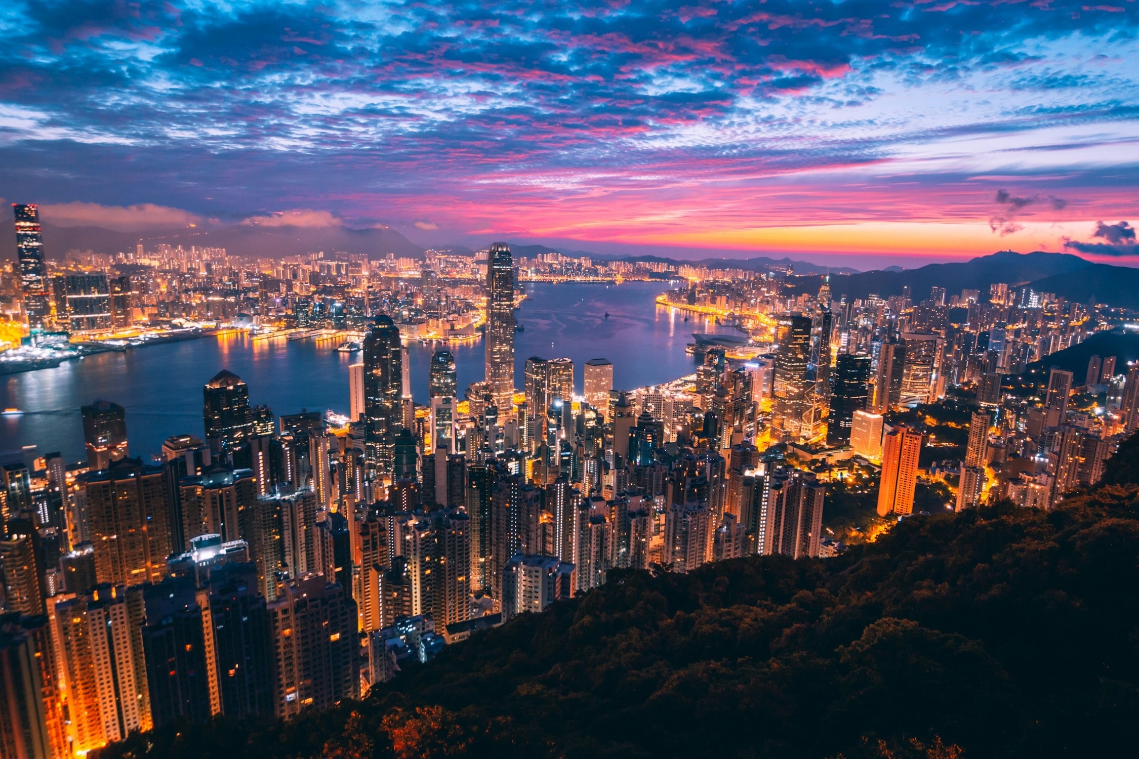 View of Hong Kong lit up, underneath a late sunset from Victoria Peak.