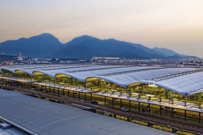 A view of the Hong Kong International Airport, with mountains and the dusk sky in the background.