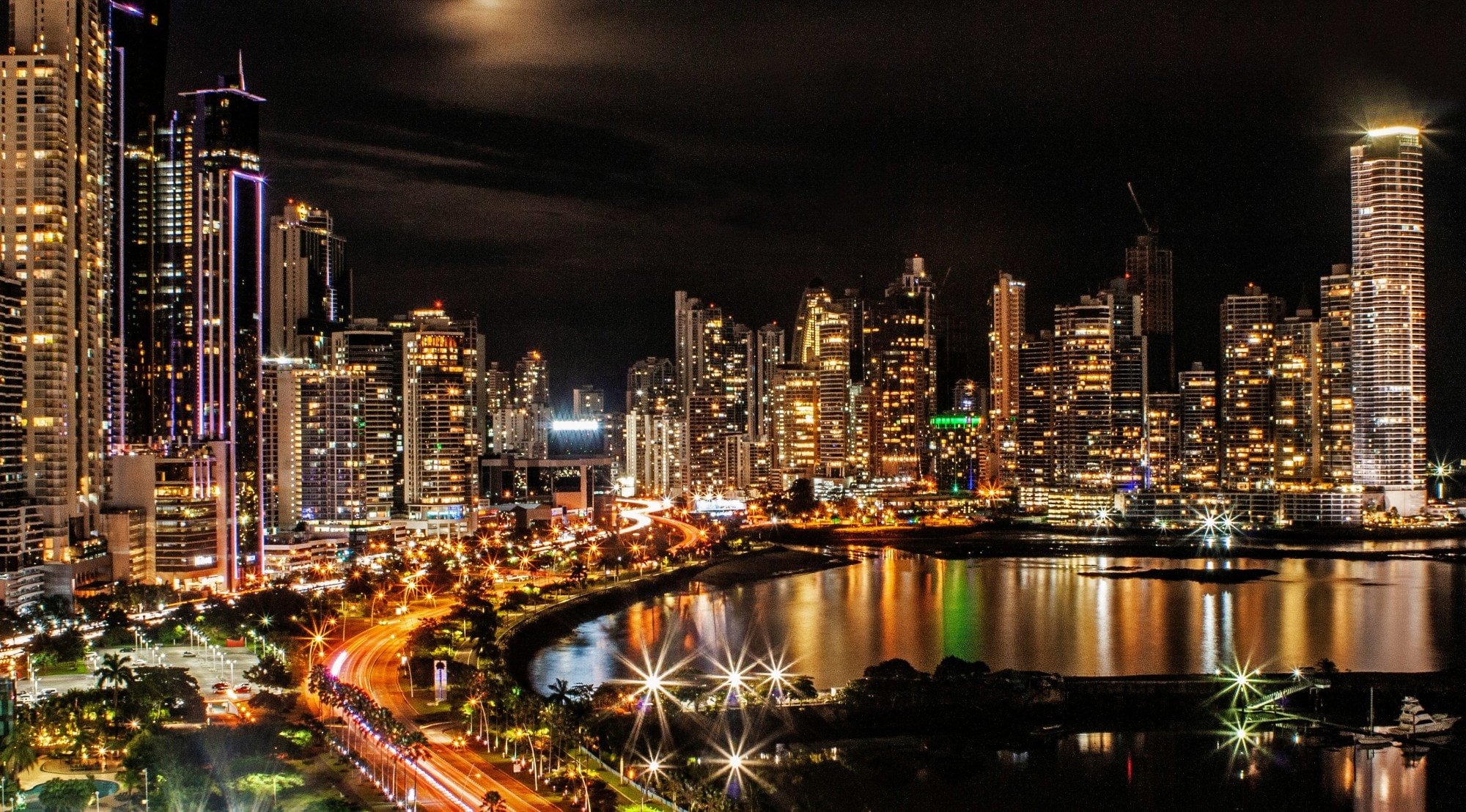 The Panama City skyline and coastline at night, with the tall buildings and streets all lit up. 