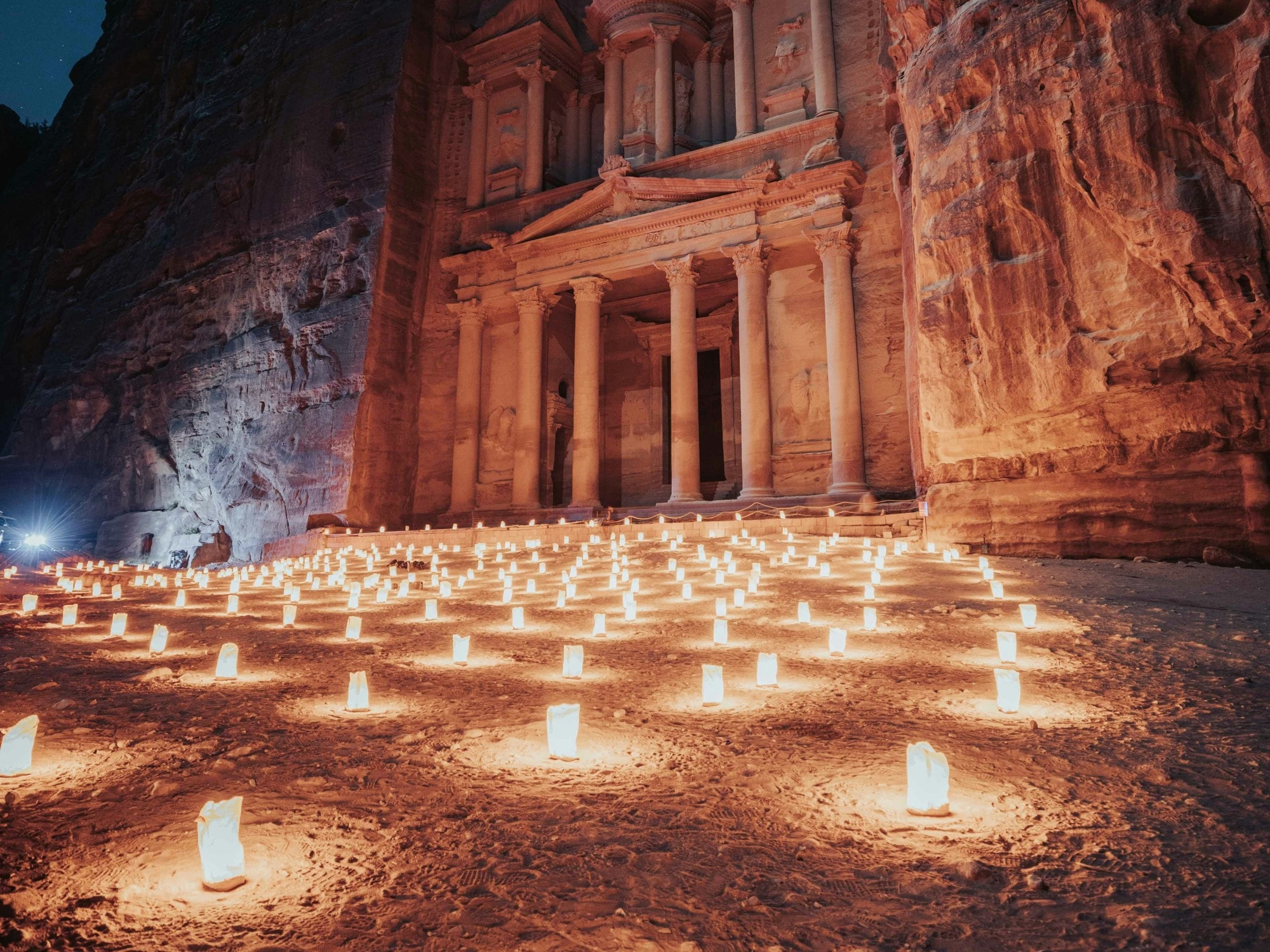 Candles on floor near ruins of an old building at night.