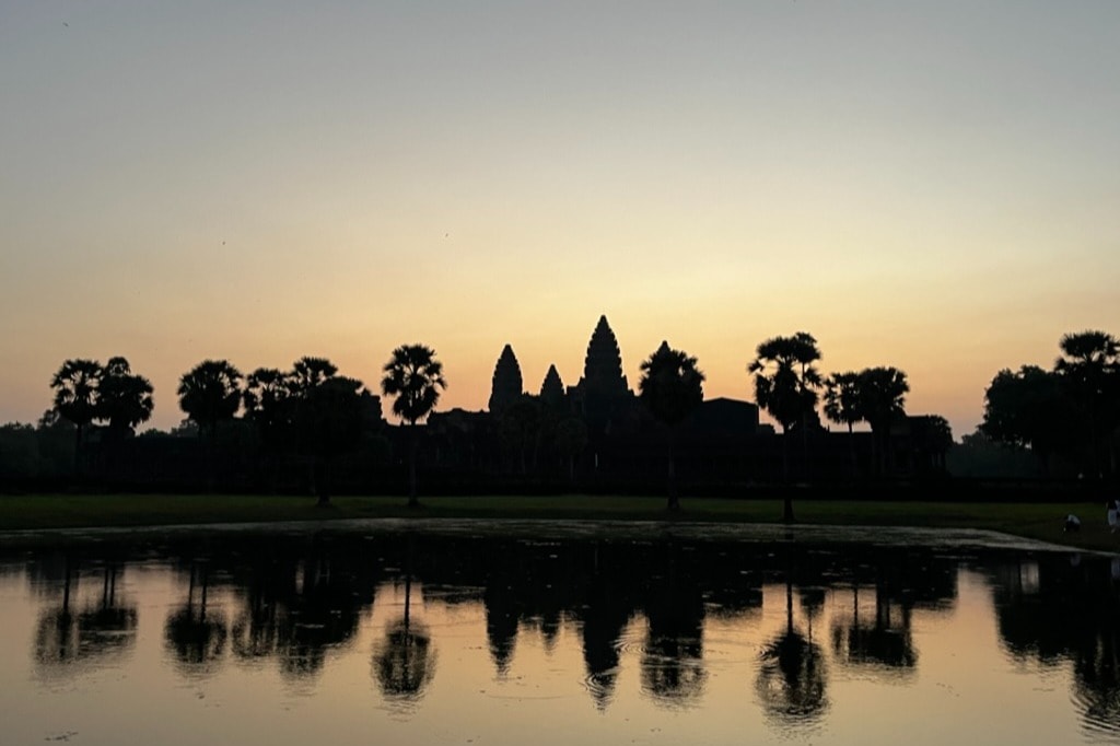 A tranquil sunrise over Angkor Wat, with the temple’s silhouette mirrored in the water.