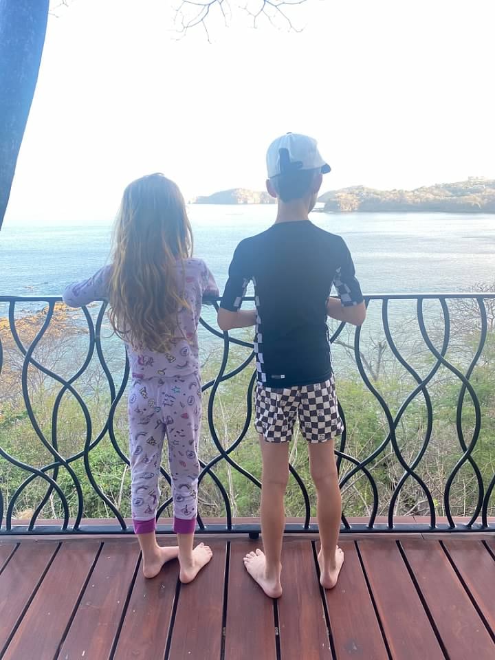 Lauren's children standing on a balcony overlooking the water.