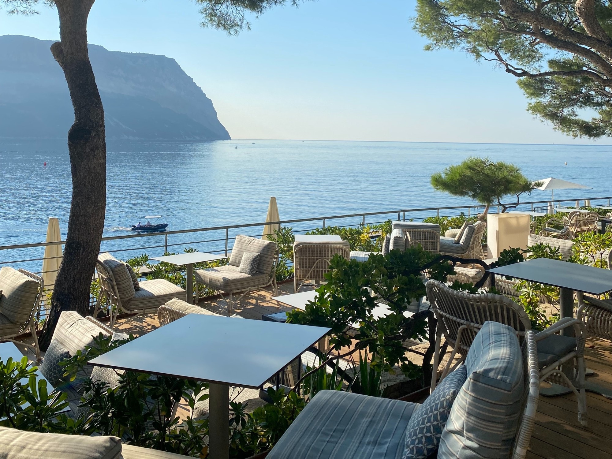 An outdoor restaurant with seating with gray cushions by the sea