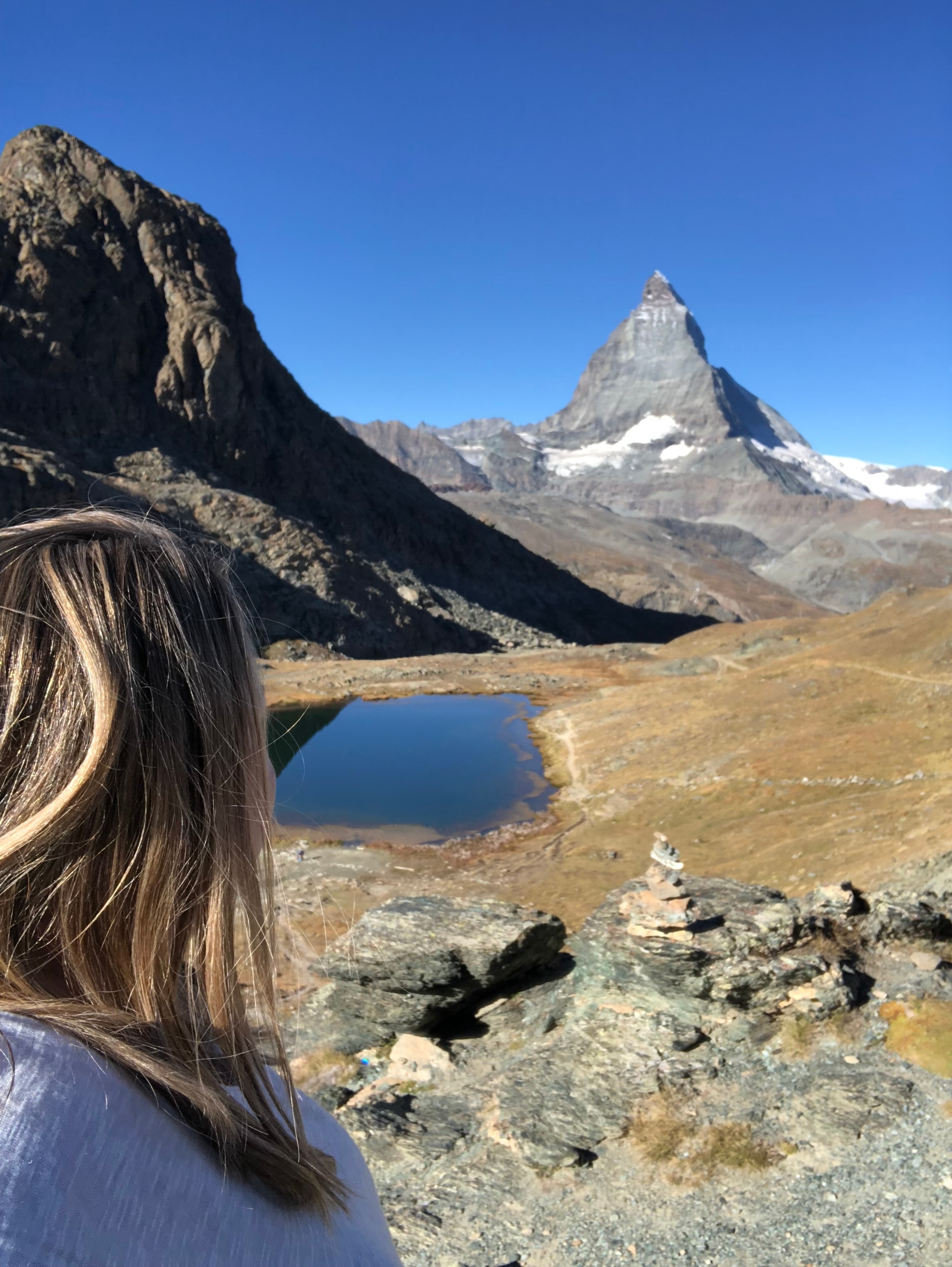 Travel advisor Amy looking at a view of Riffelsee lake with snow-capped mountains behind