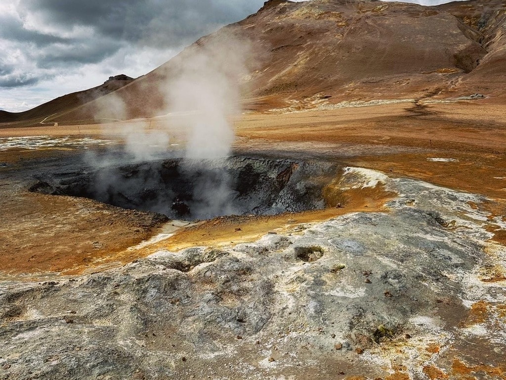 A steaming pool of water in a brown field