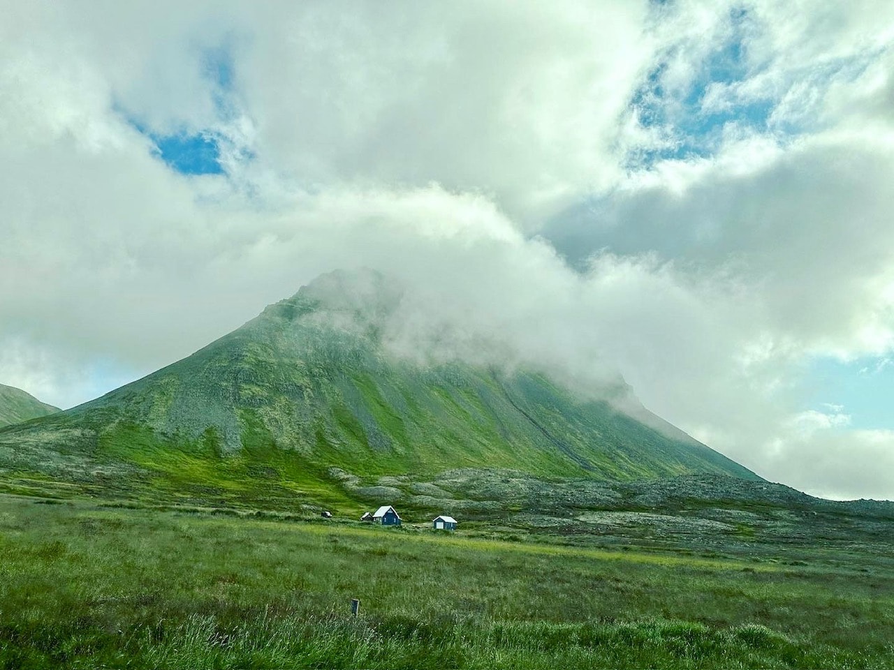 Green field with mountain and cloud on top.