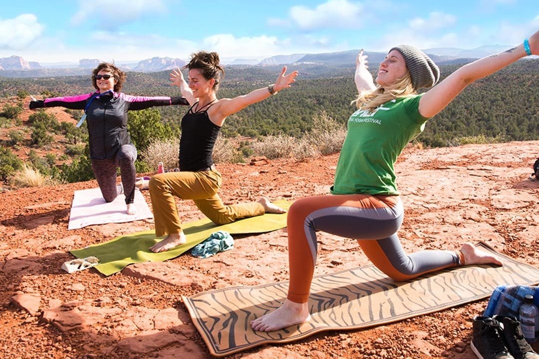 A picture of people doing yoga on a mountain during the daytime.