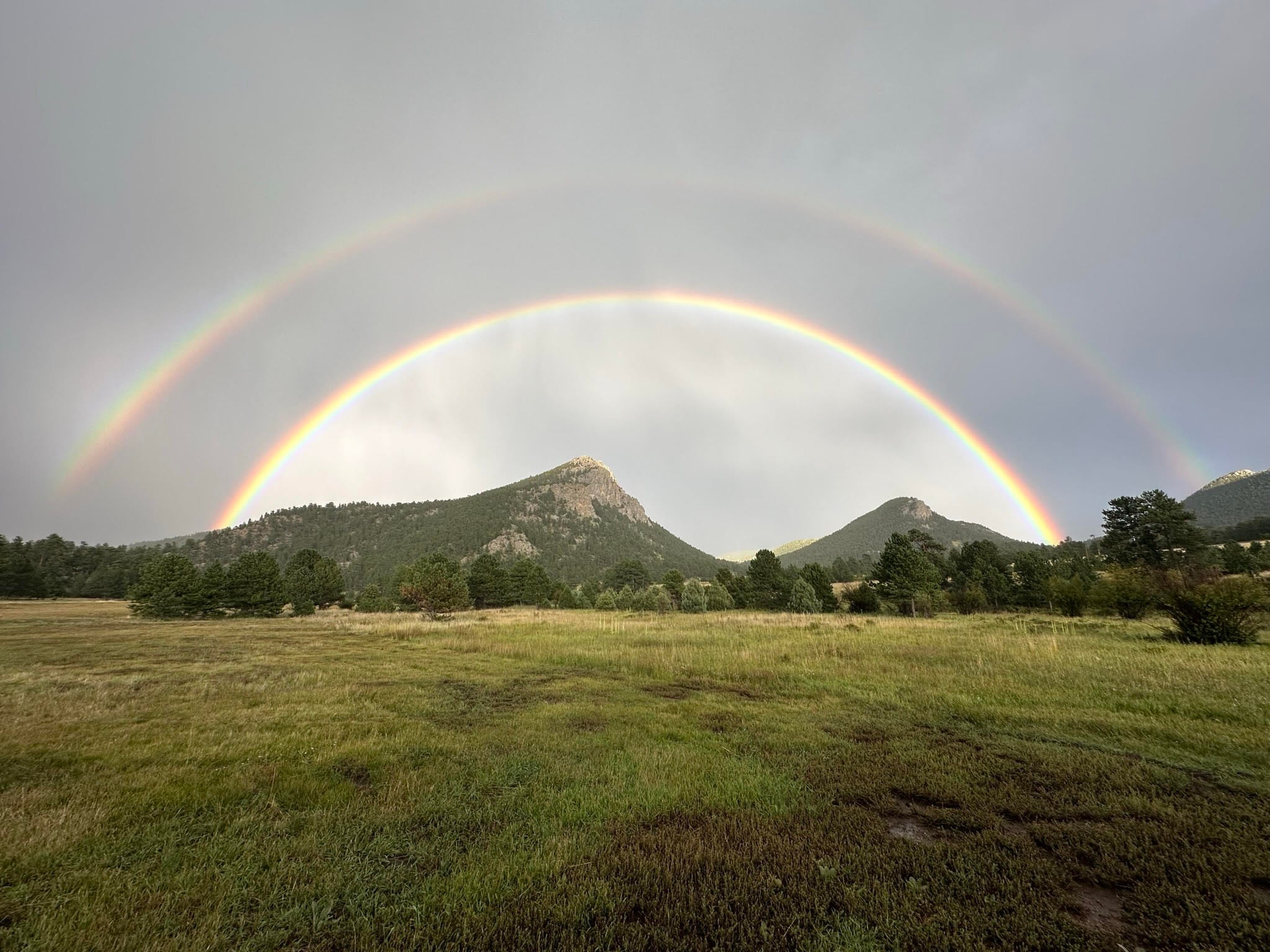 Beautiful view of double rainbow over a field and mountains