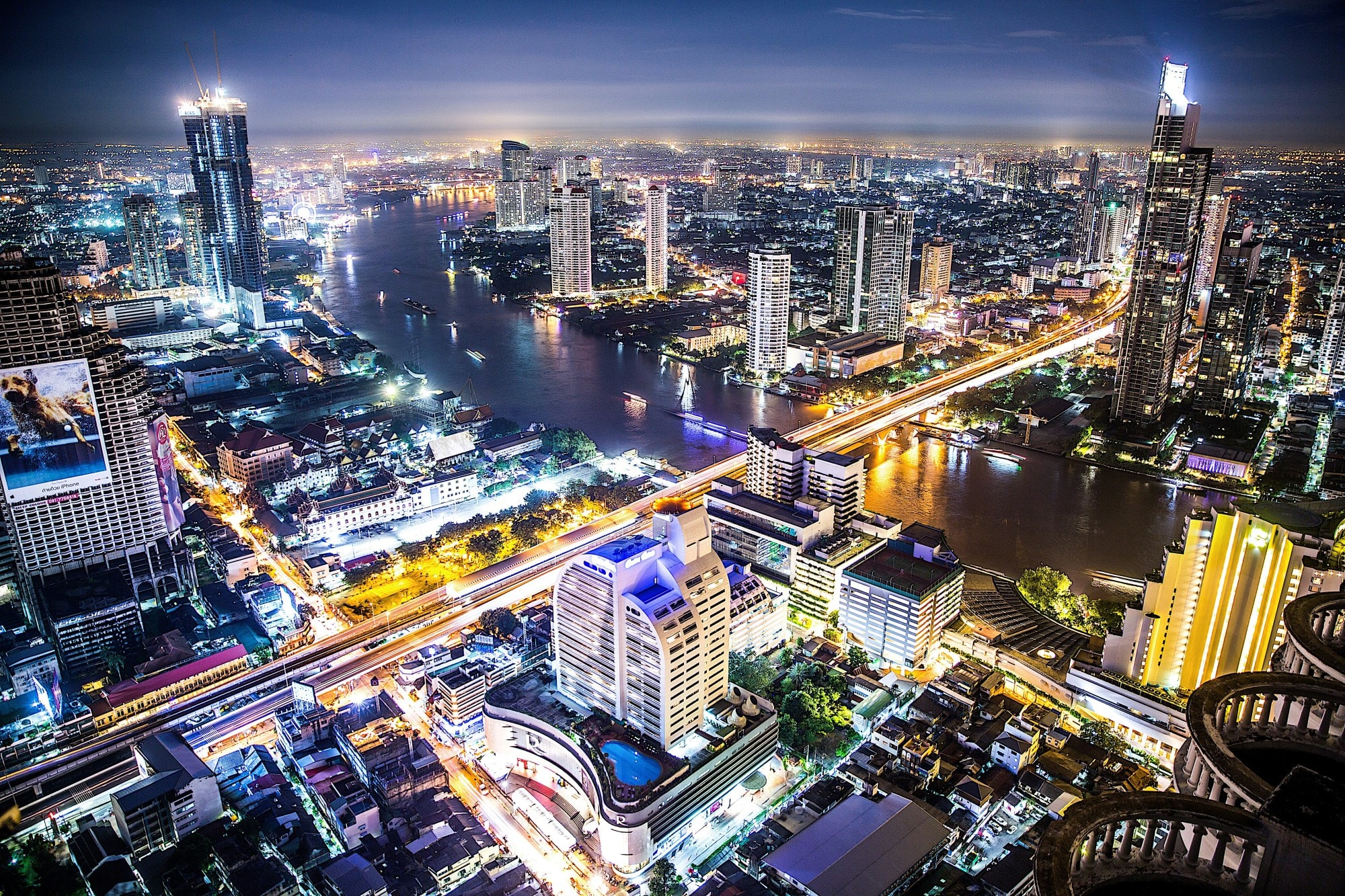 Overview of city skyline with Bangkok buildings and waterbody at night.