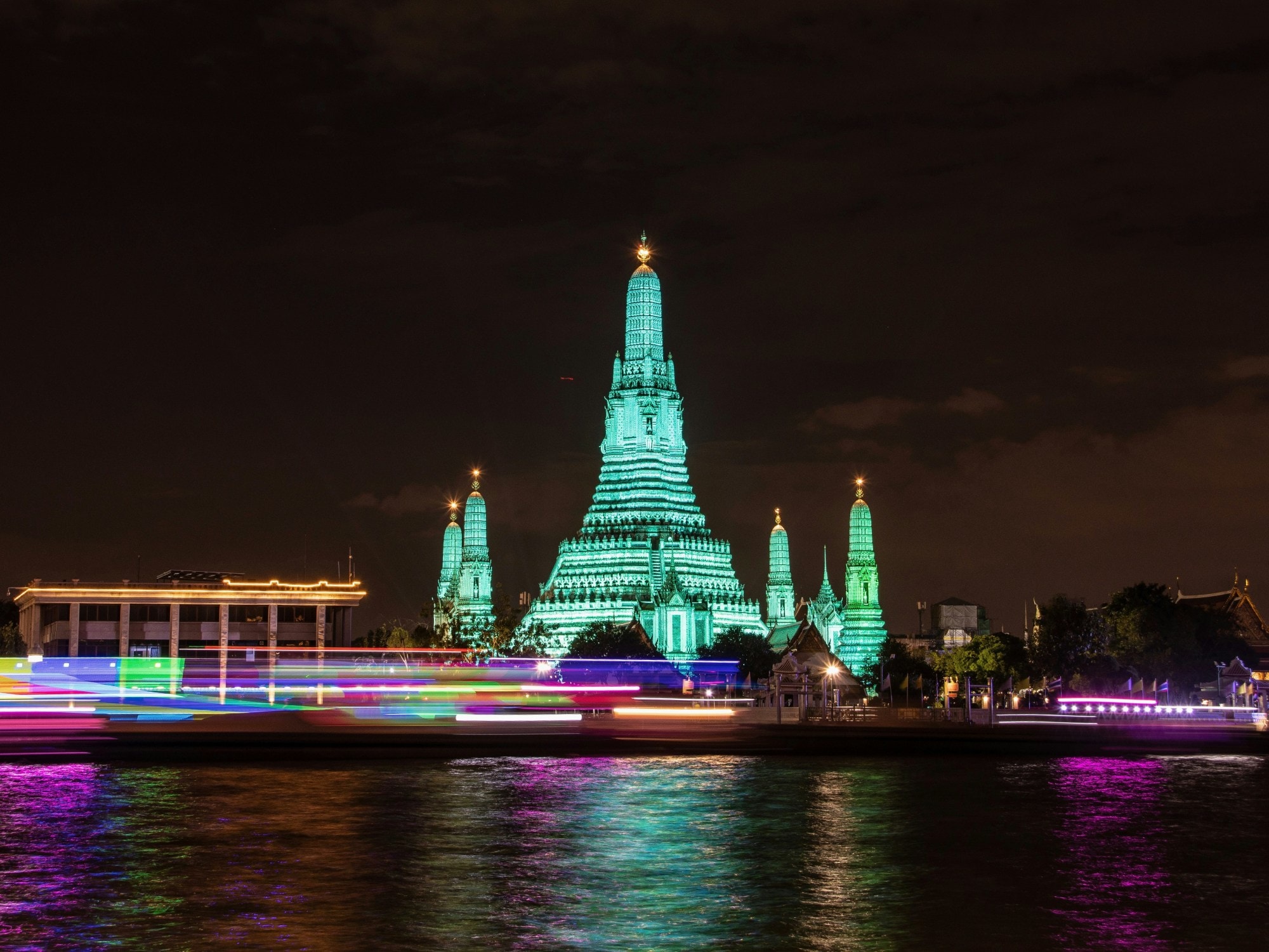 Blue colored lit towers at night in front of a water body.