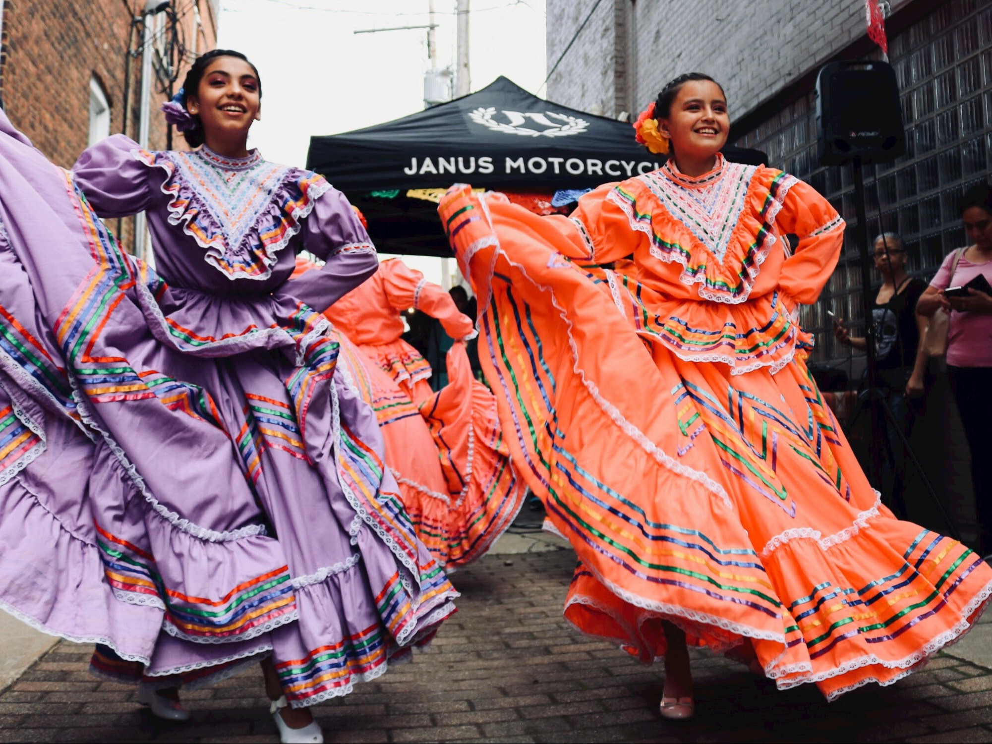 A picture of a Flamenco show with women dancing in colorful dresses in an alleyway.