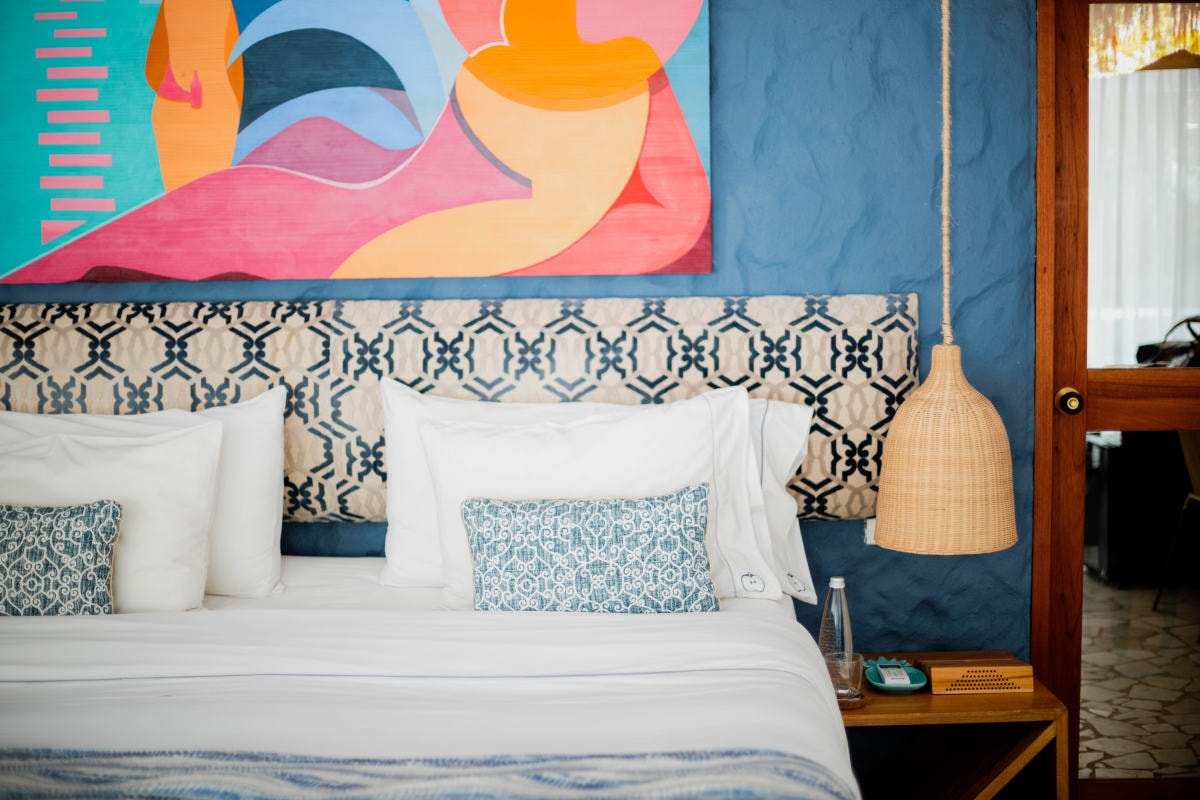 bed against a blue wall with a colorful painting