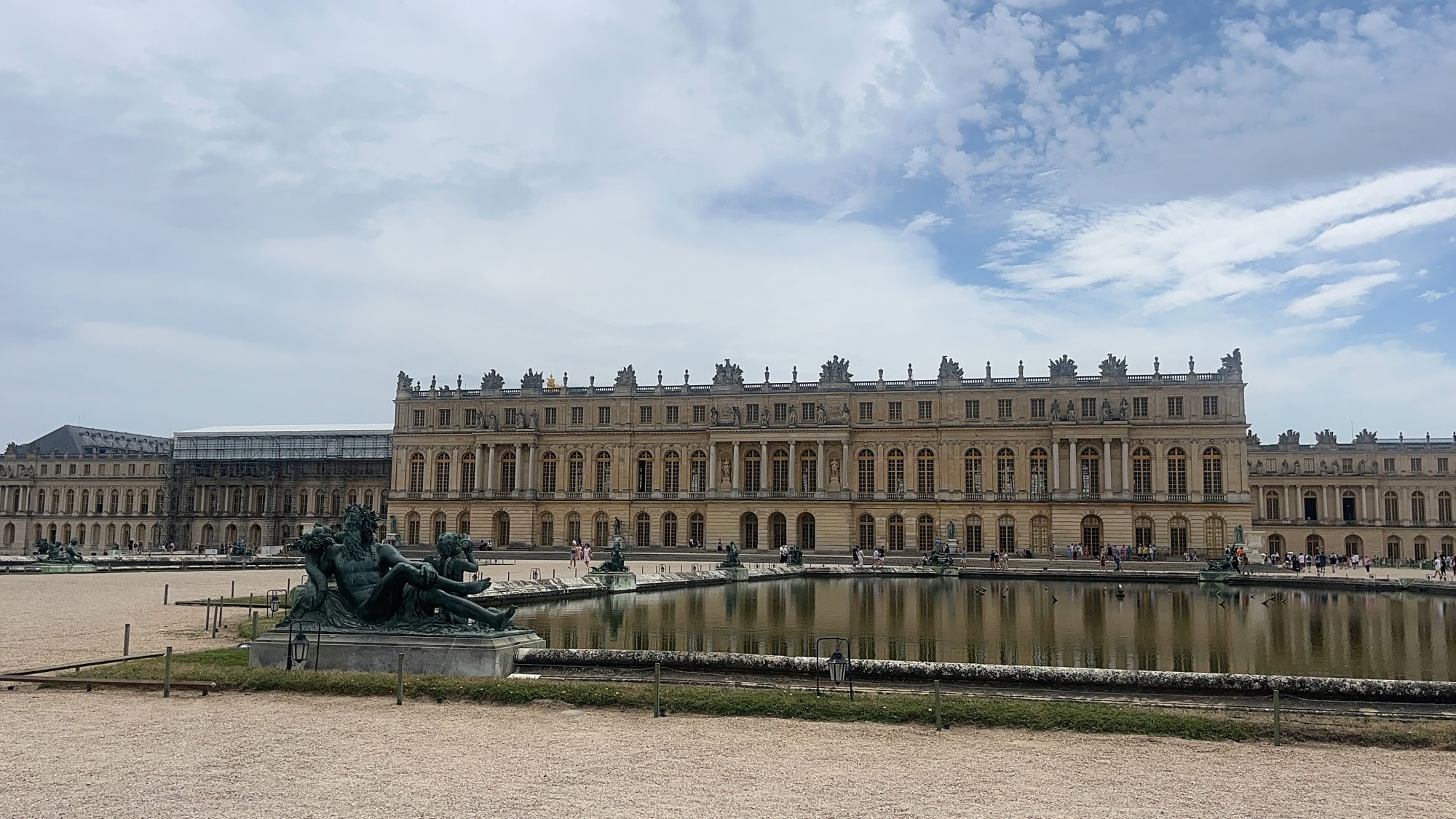 A palace with pool and statues in front.