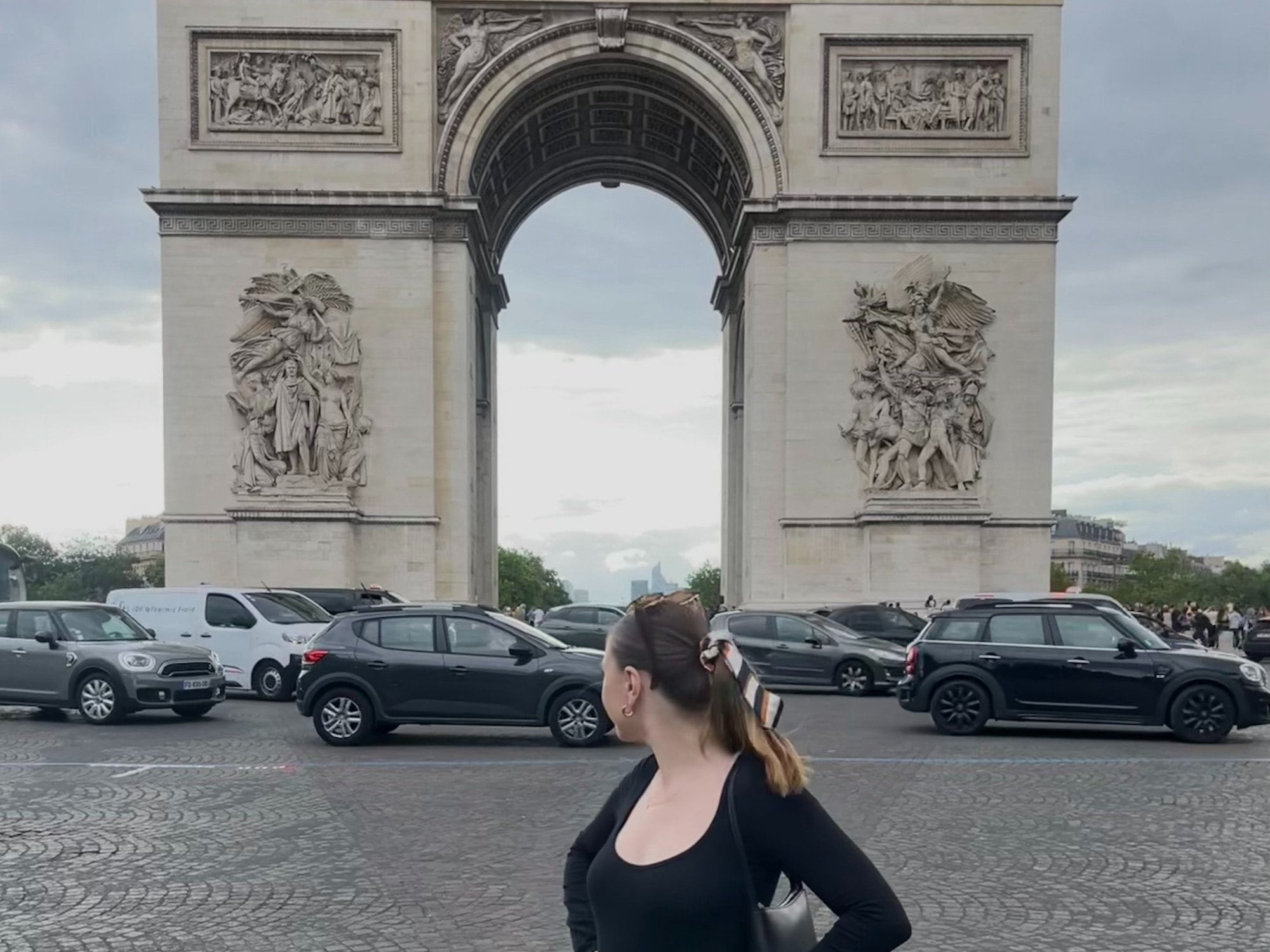 A woman in black dress standing in front of a large cement arch 