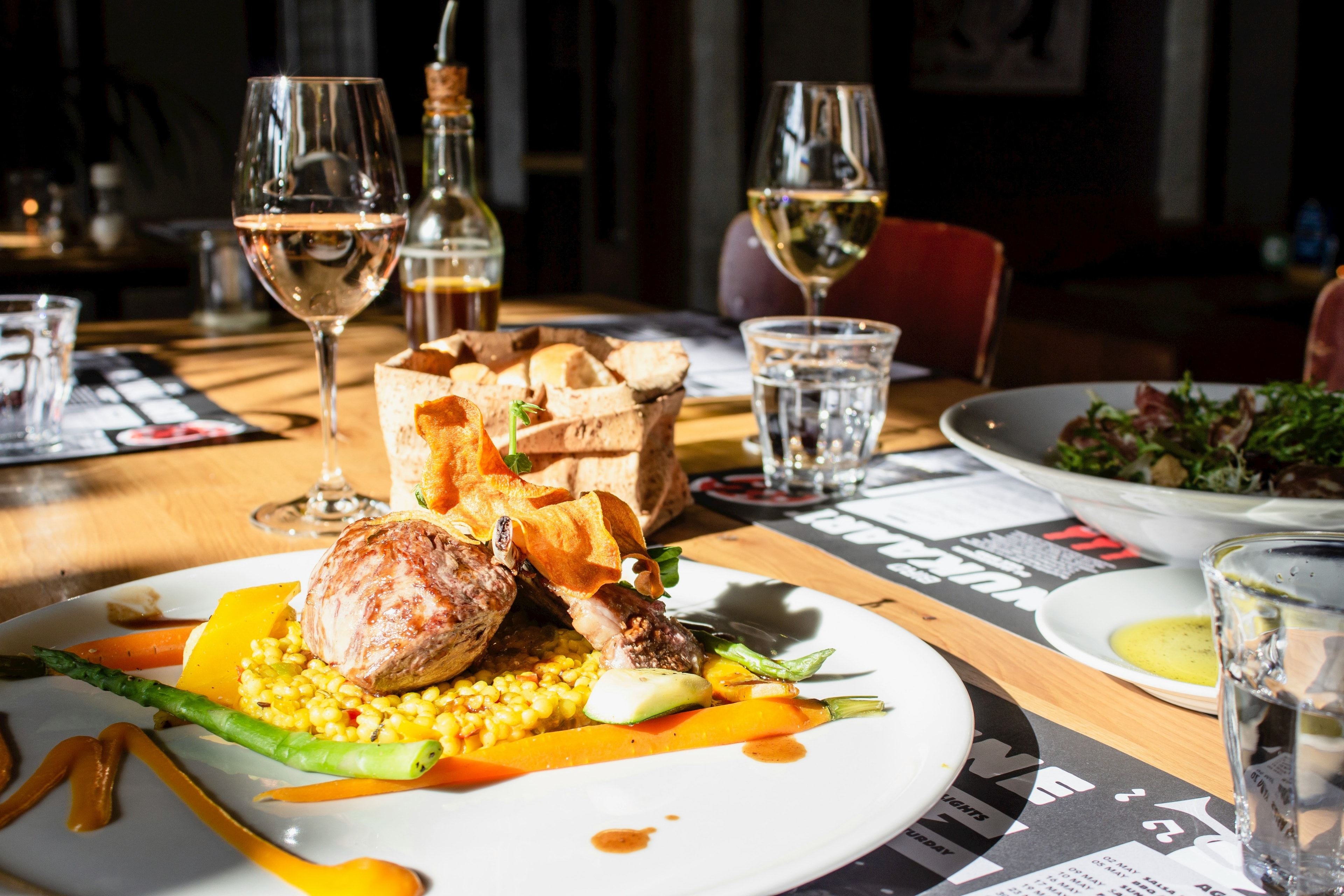 A picture of food served near wine glasses on a table at a restaurant.