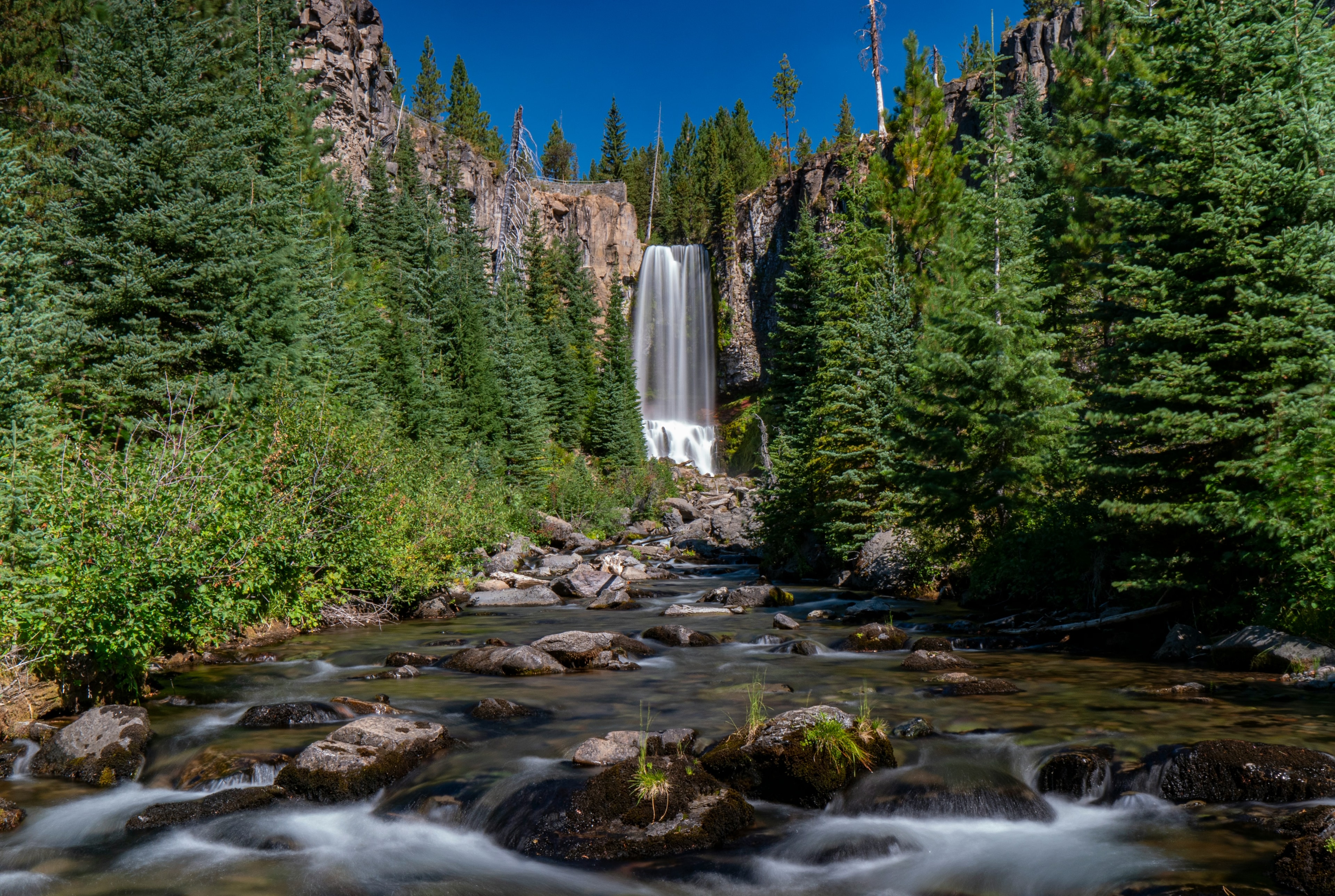 A river with a waterfall and green trees on either side