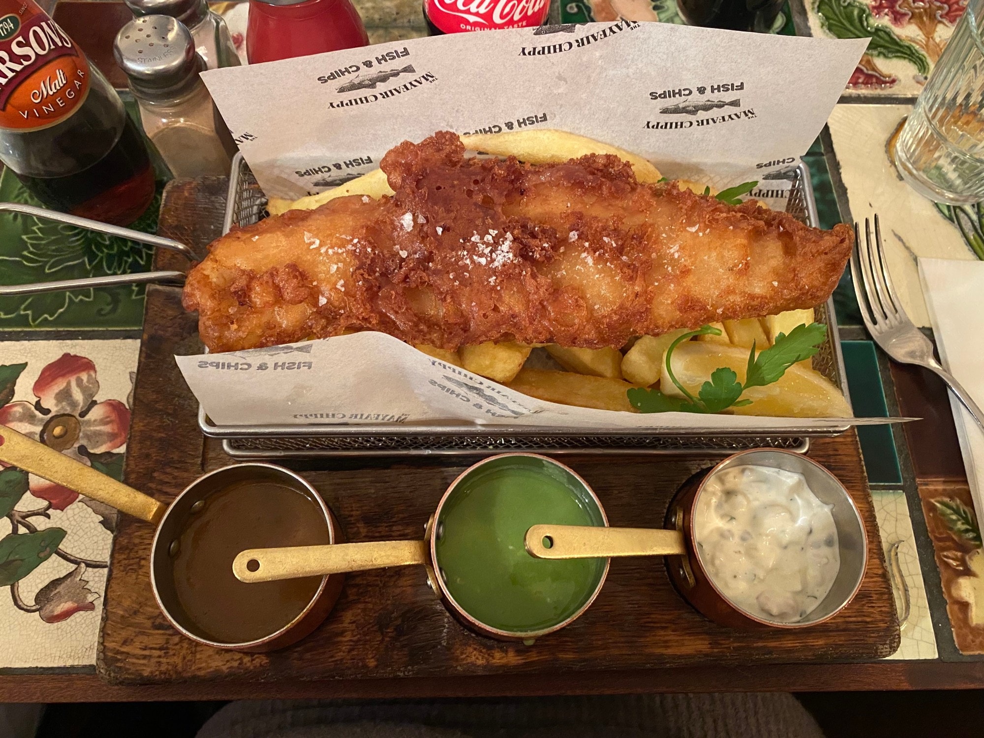 Fish and chips with three sauces in a paper tray.