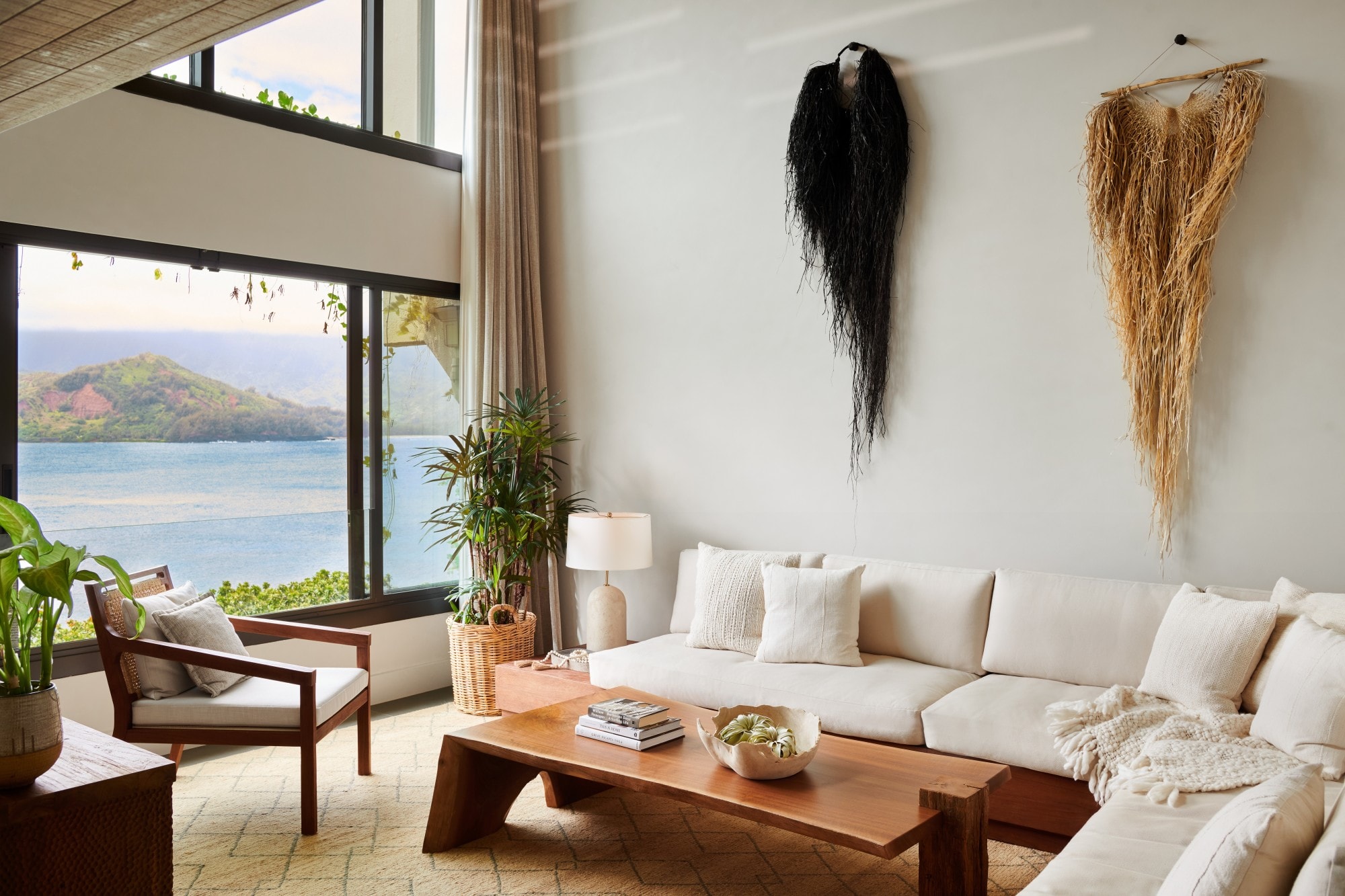 an airy living room with white furniture and a wooden coffee table overlooking the ocean