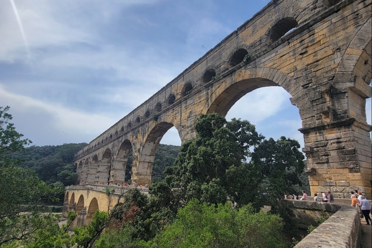 A picture of people walking on a concrete arch above a bridge.