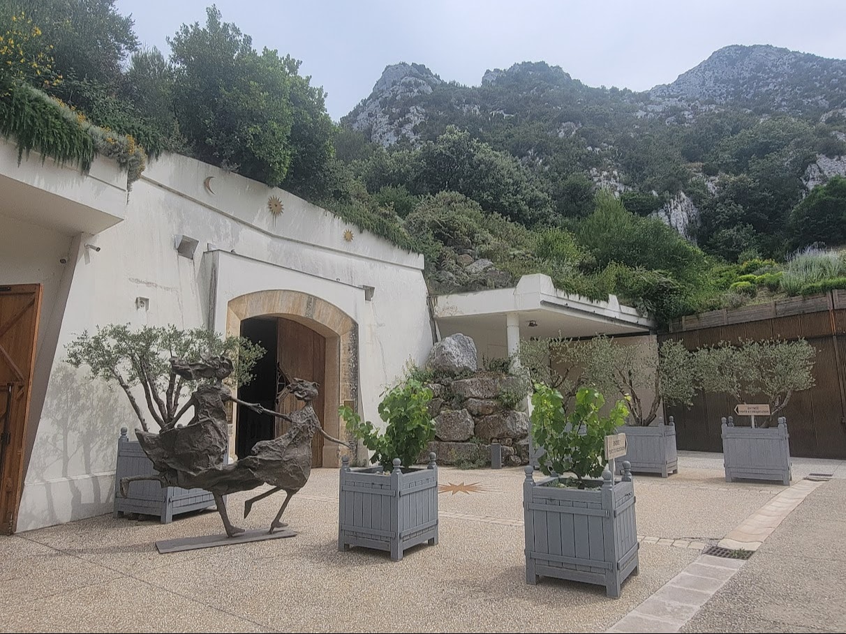 The white facade of a building near tree-covered hills