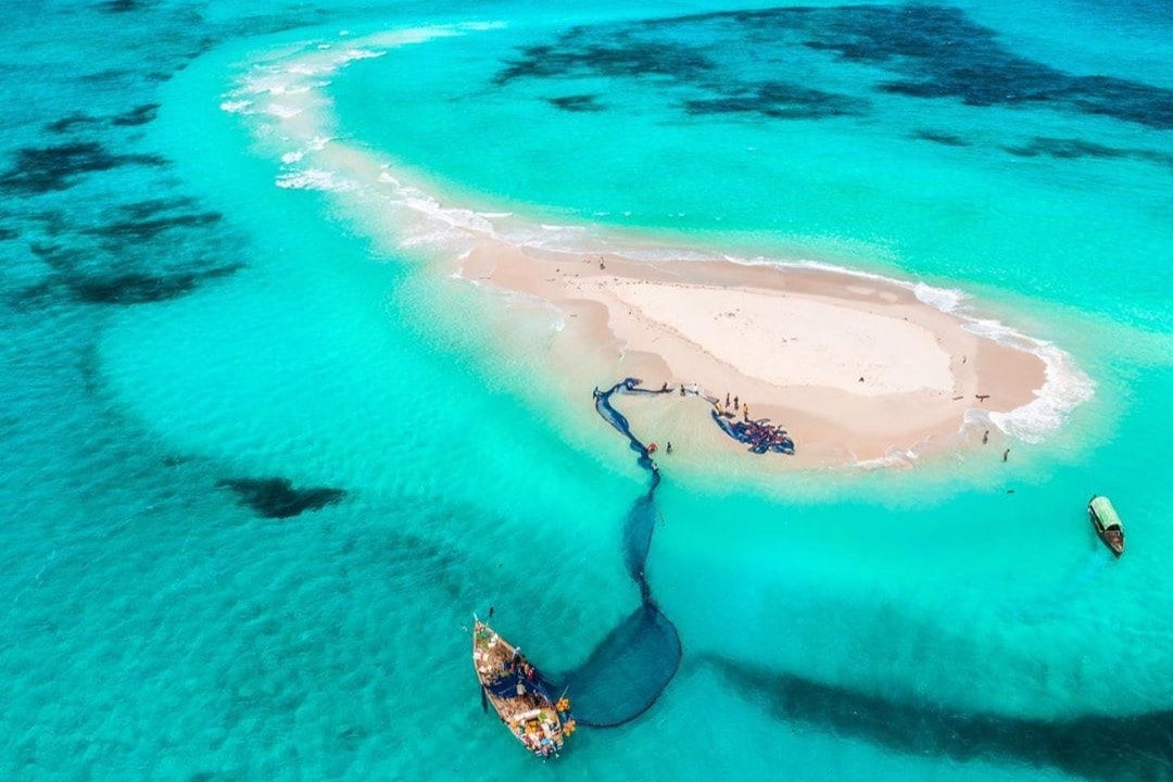 Aerial view of a small sandy island in the middle of a body of water 