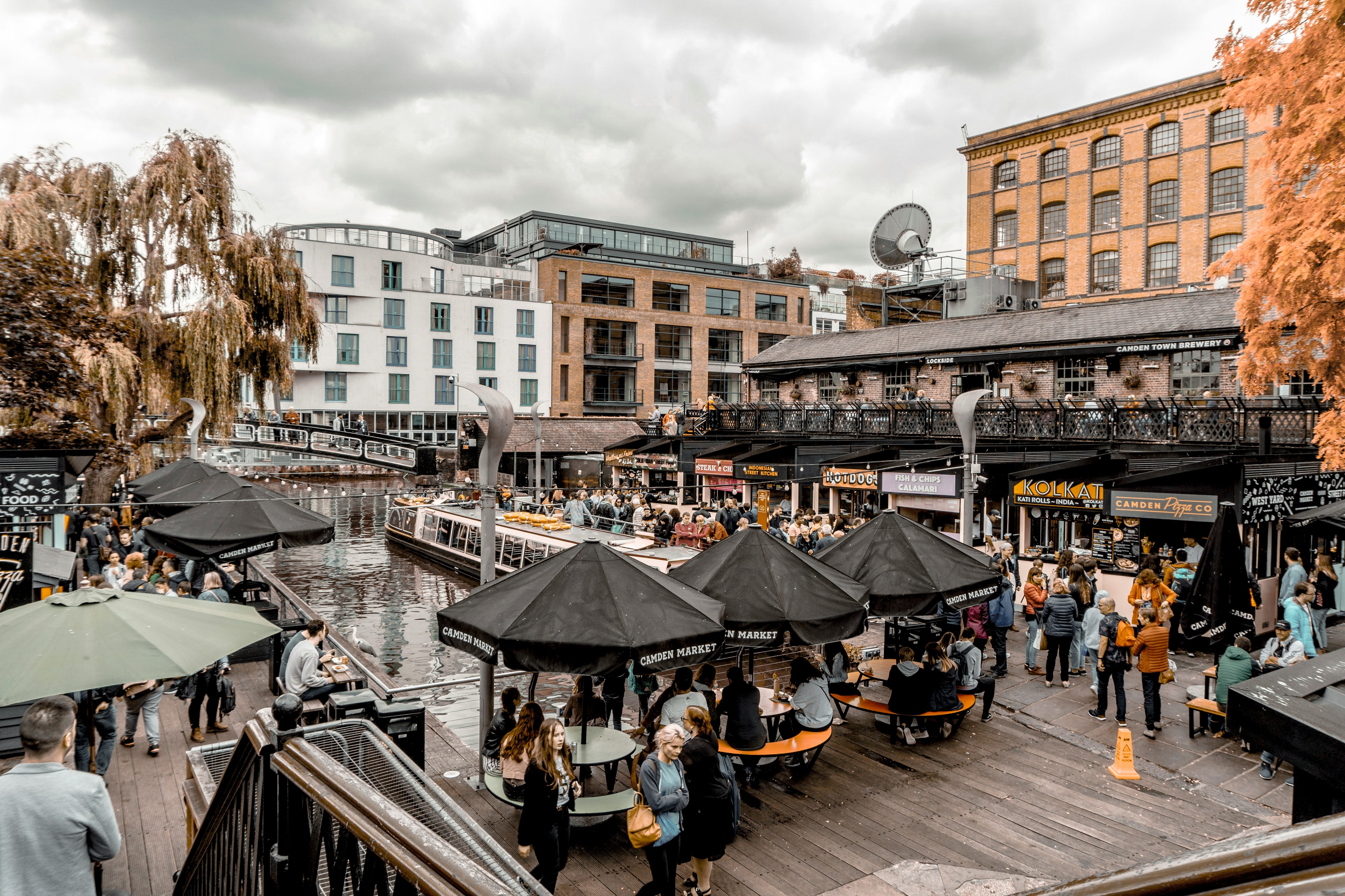 People sitting at outside tables near a dock during the daytime