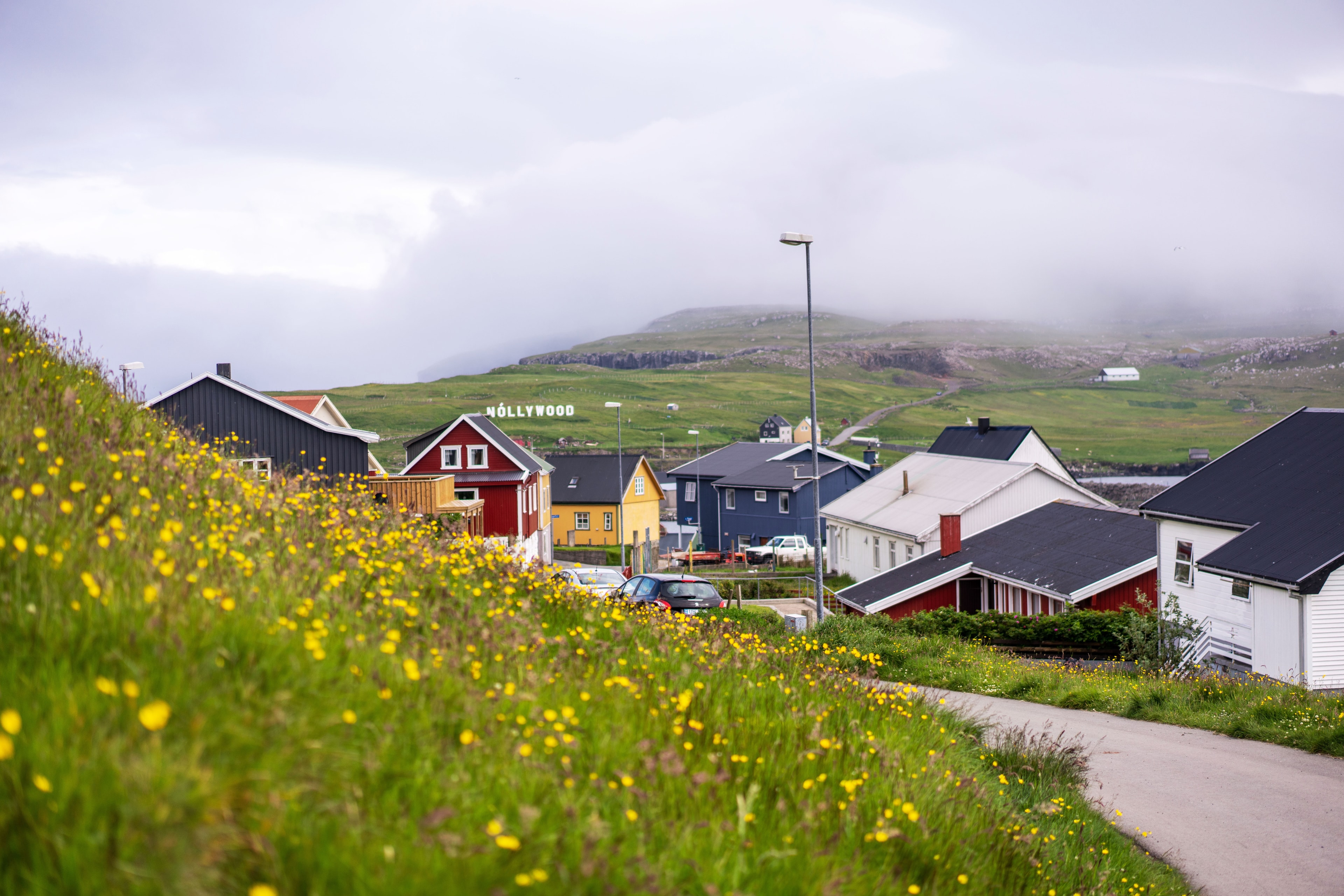 A small village of colorful homes next to a grassy hill