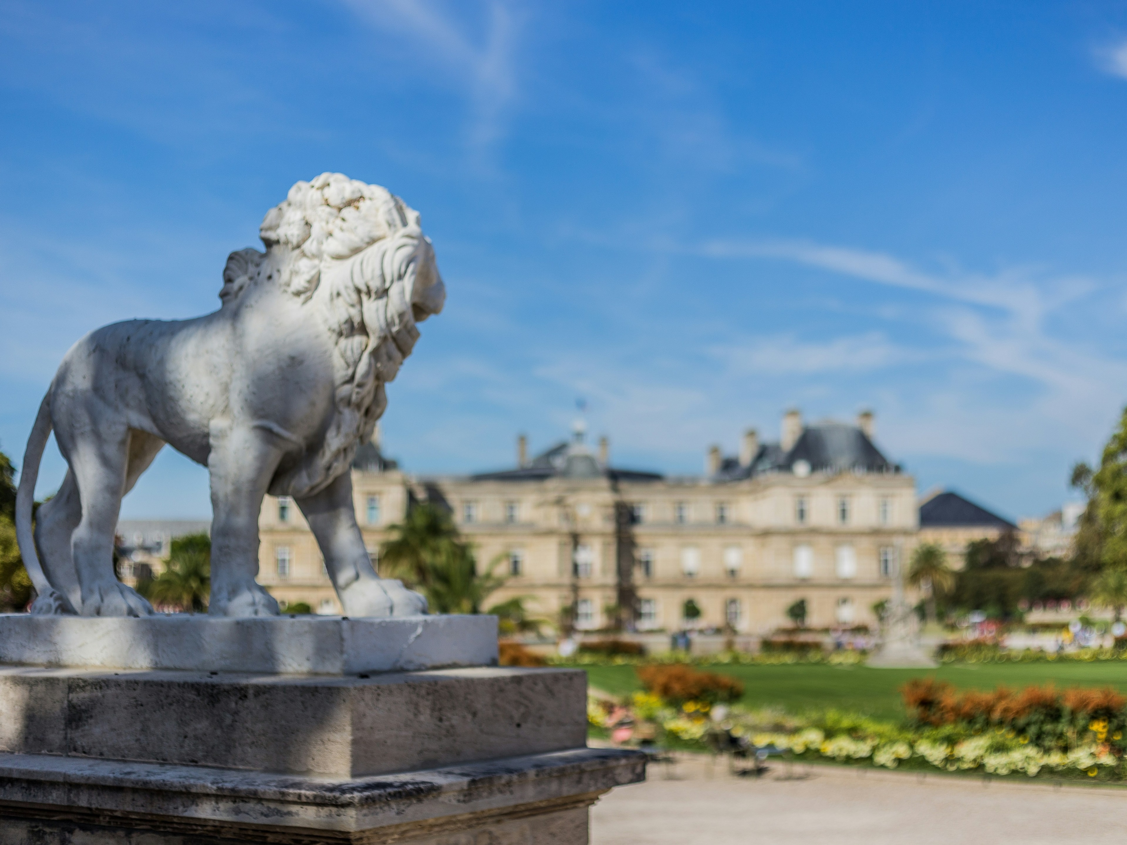 A far view of the Luxembourg Gardens with huge concrete statue of a lion in the front.