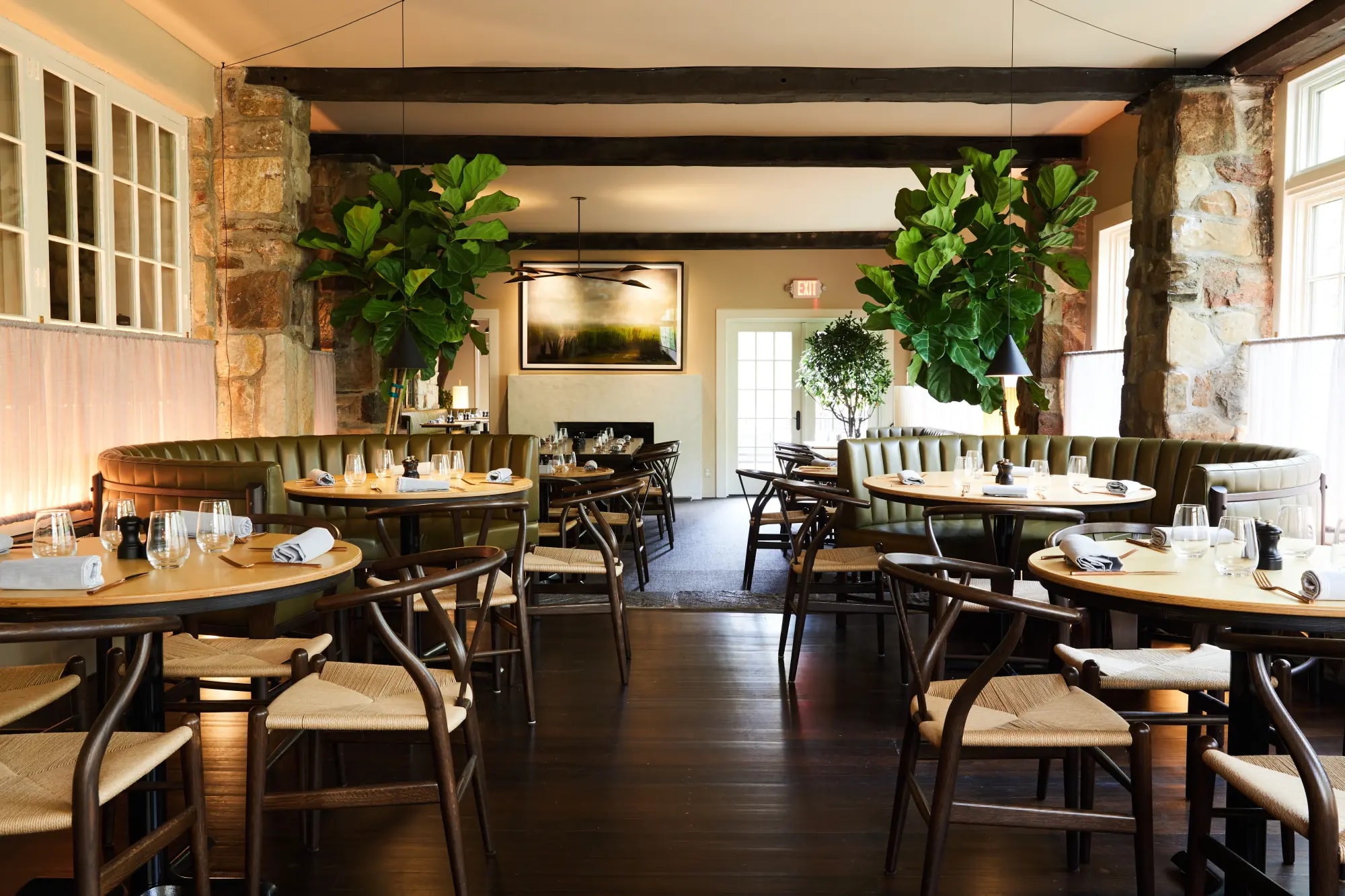 a dining room filled with round tables and green leafy decorative trees