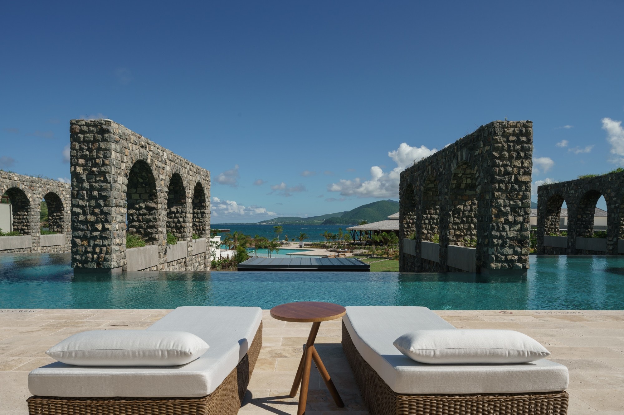 two gray daybeds near a pool overlooking the ocean