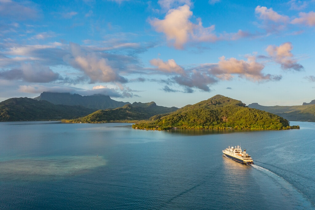 aerial view of a ship in tropical waters dotted with green islands