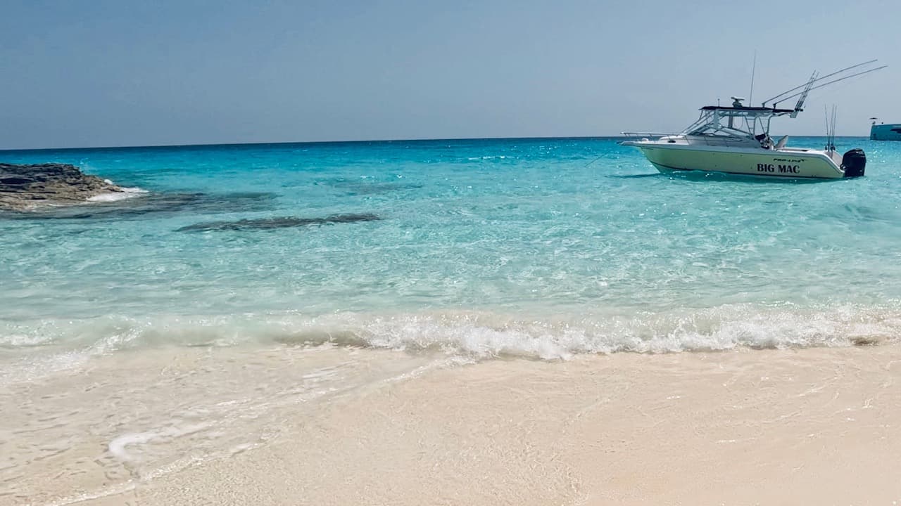 Picture of a yacht on crystal clear water near a white sand beach