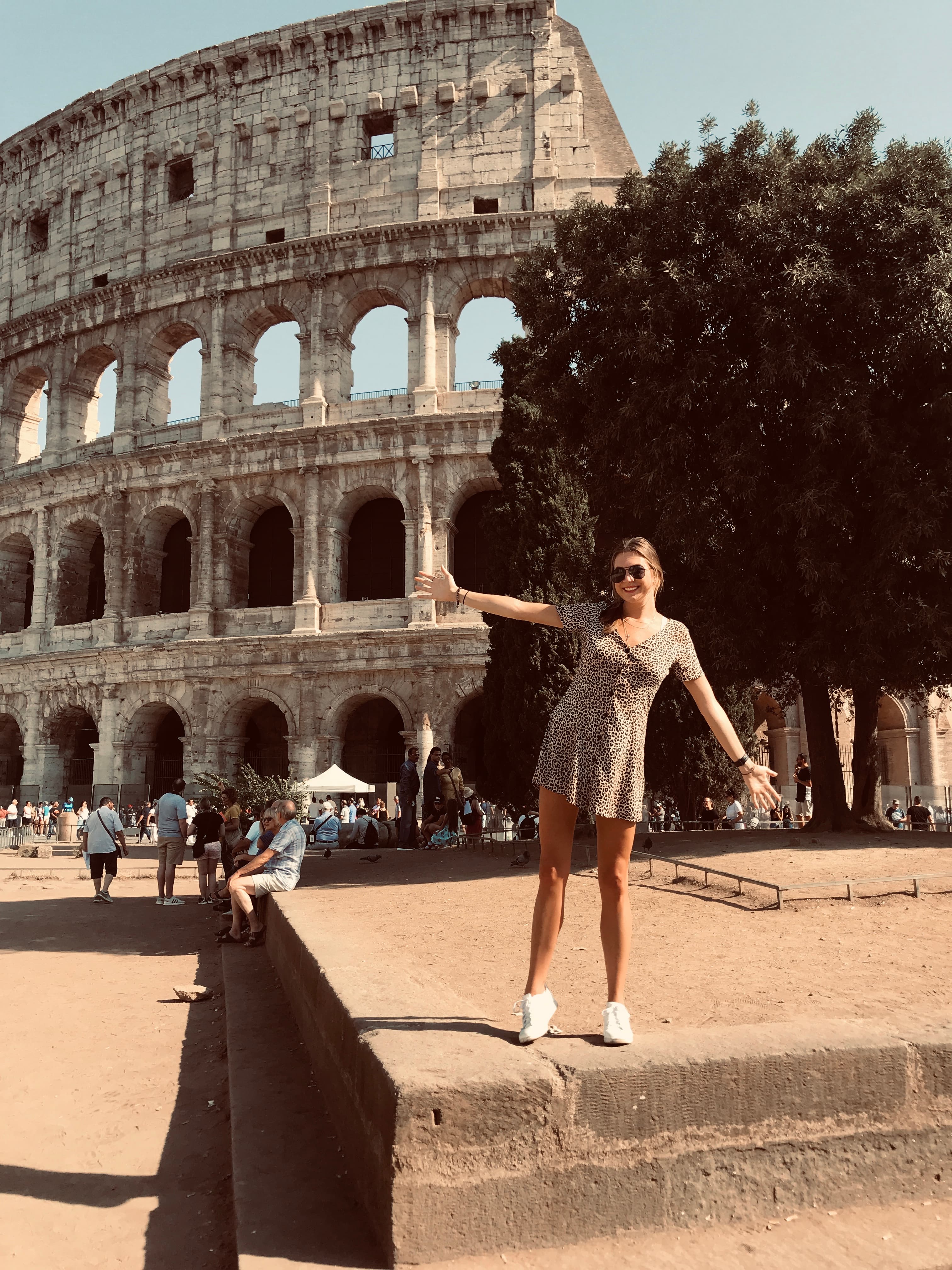 Lauren posing on a sunny day with outstretched arms in front of Rome's Coliseum.